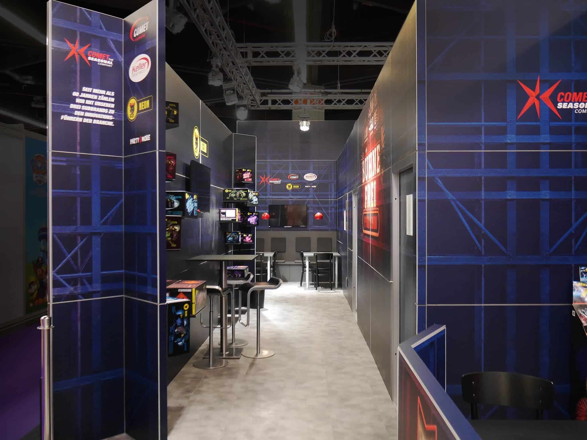 Sitzbereich und Produktpräsentation im Comet Messestand mit blauem Wanddesign – Messebau Nürnberg