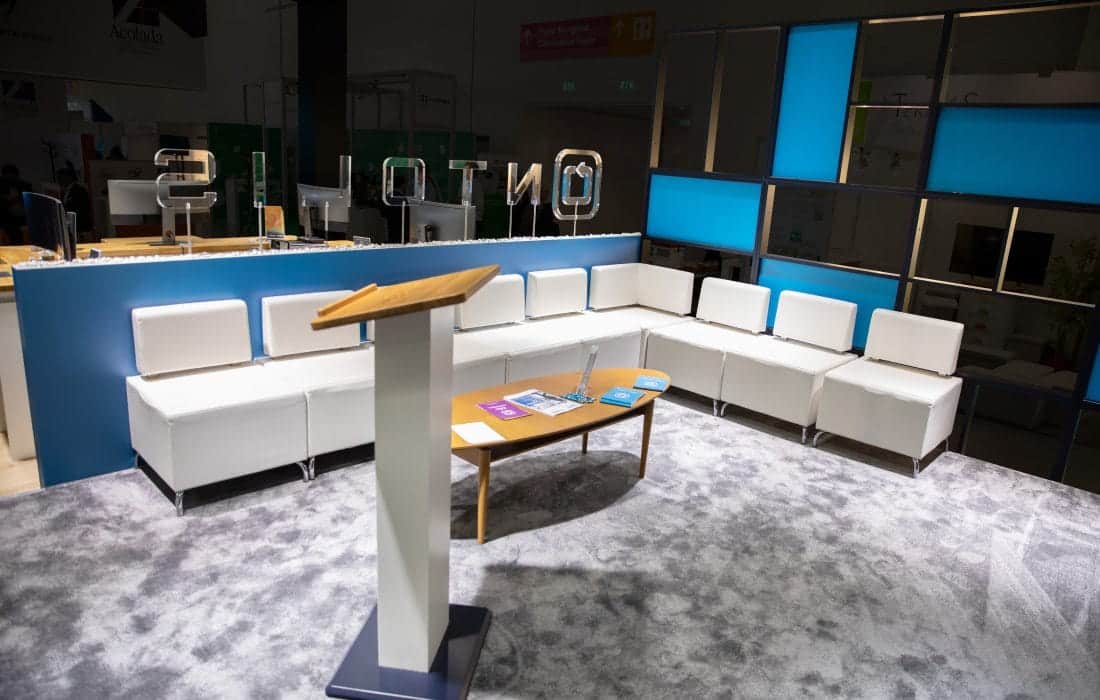Lounge-Bereich des Ontolis Messestands auf der ICS Messe Stuttgart mit weißen Sofas.