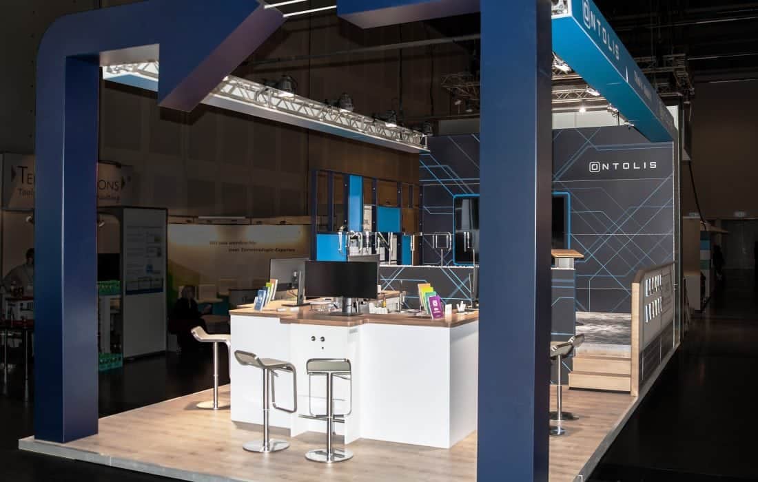 ICS Messebau Stuttgart – Messestand von Ontolis mit dunklem Design und Holzelementen.