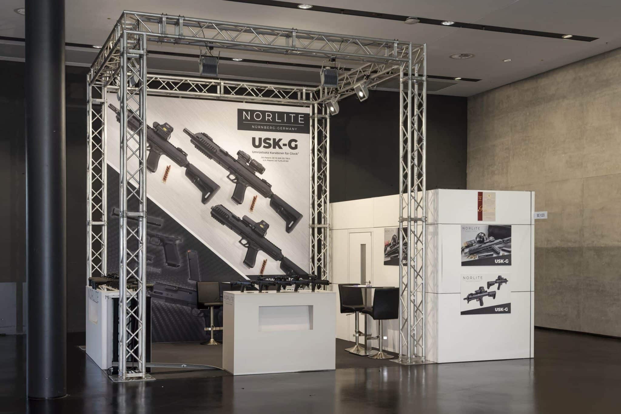 Norlite Messestand mit USK-G Waffenpräsentation und Sitzbereich auf der IWA OutdoorClassics in Nürnberg.