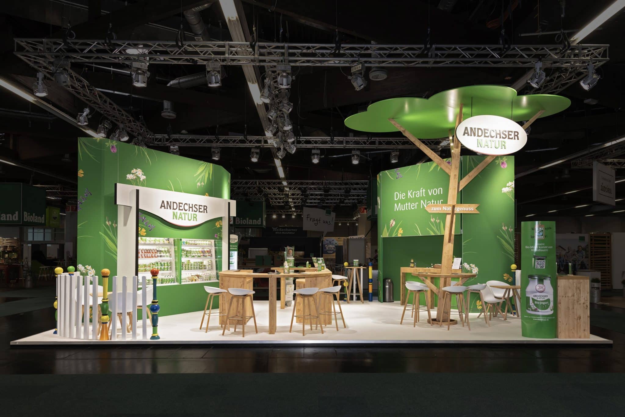Frontalansicht des Andechser Natur Stands mit Sitzbereichen, Holztheke und Naturdesign auf der Biofach Nürnberg – Messebau Nürnberg.