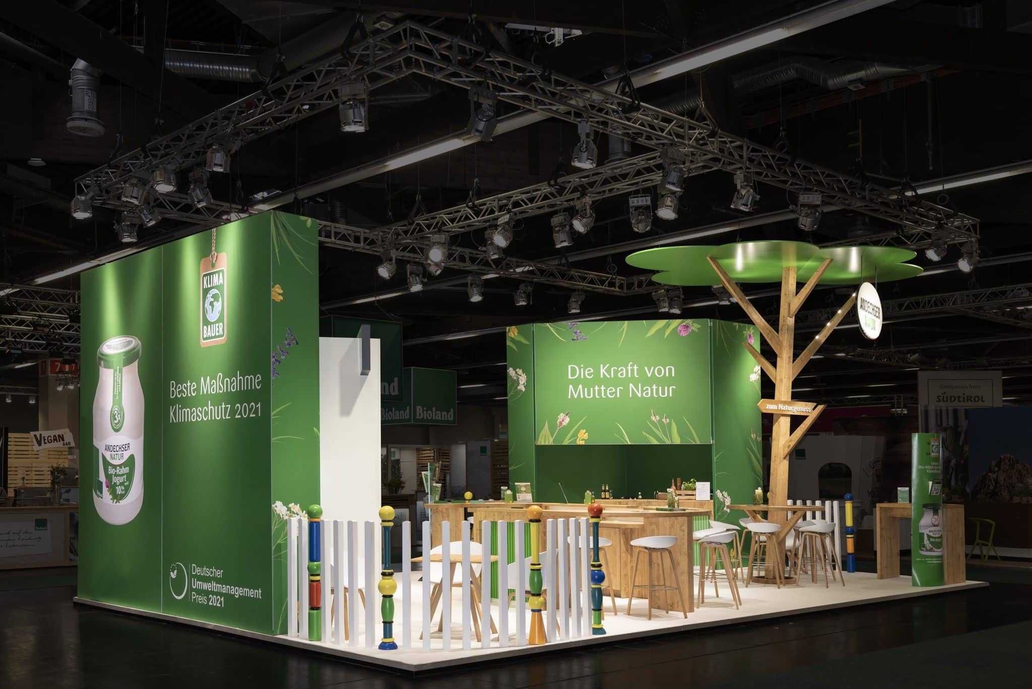 Andechser Natur Messestand mit großem Klimabauer Poster und Holztheke auf der Biofach in Nürnberg – Messebau Nürnberg.