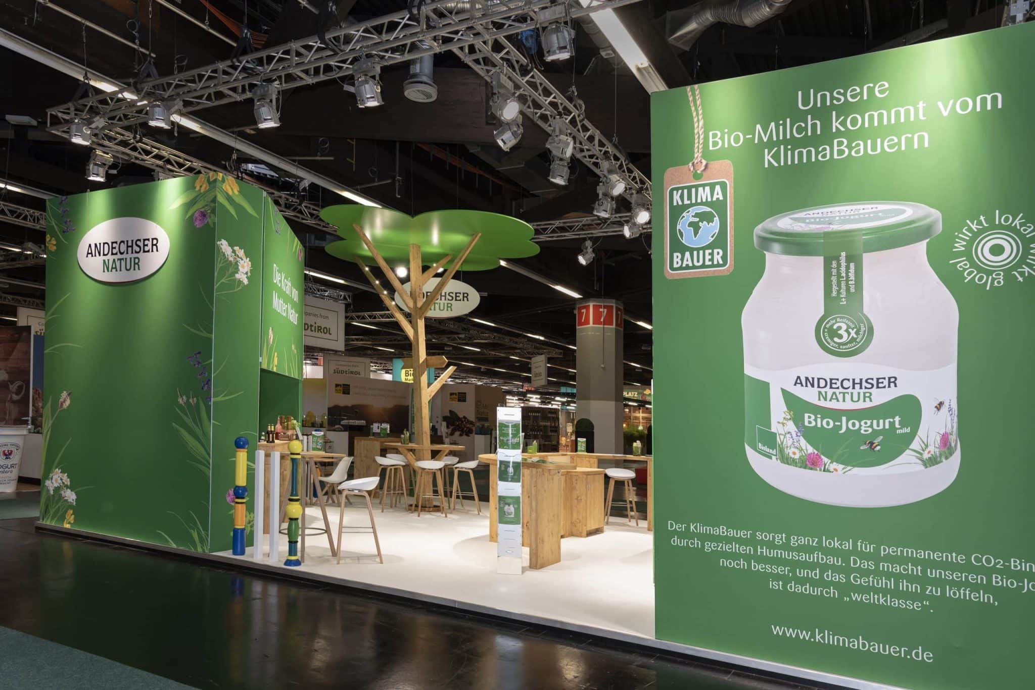 Seitenansicht des Andechser Natur Messestands mit großem Bio-Joghurt Poster auf der Biofach Nürnberg – Messebau Nürnberg.