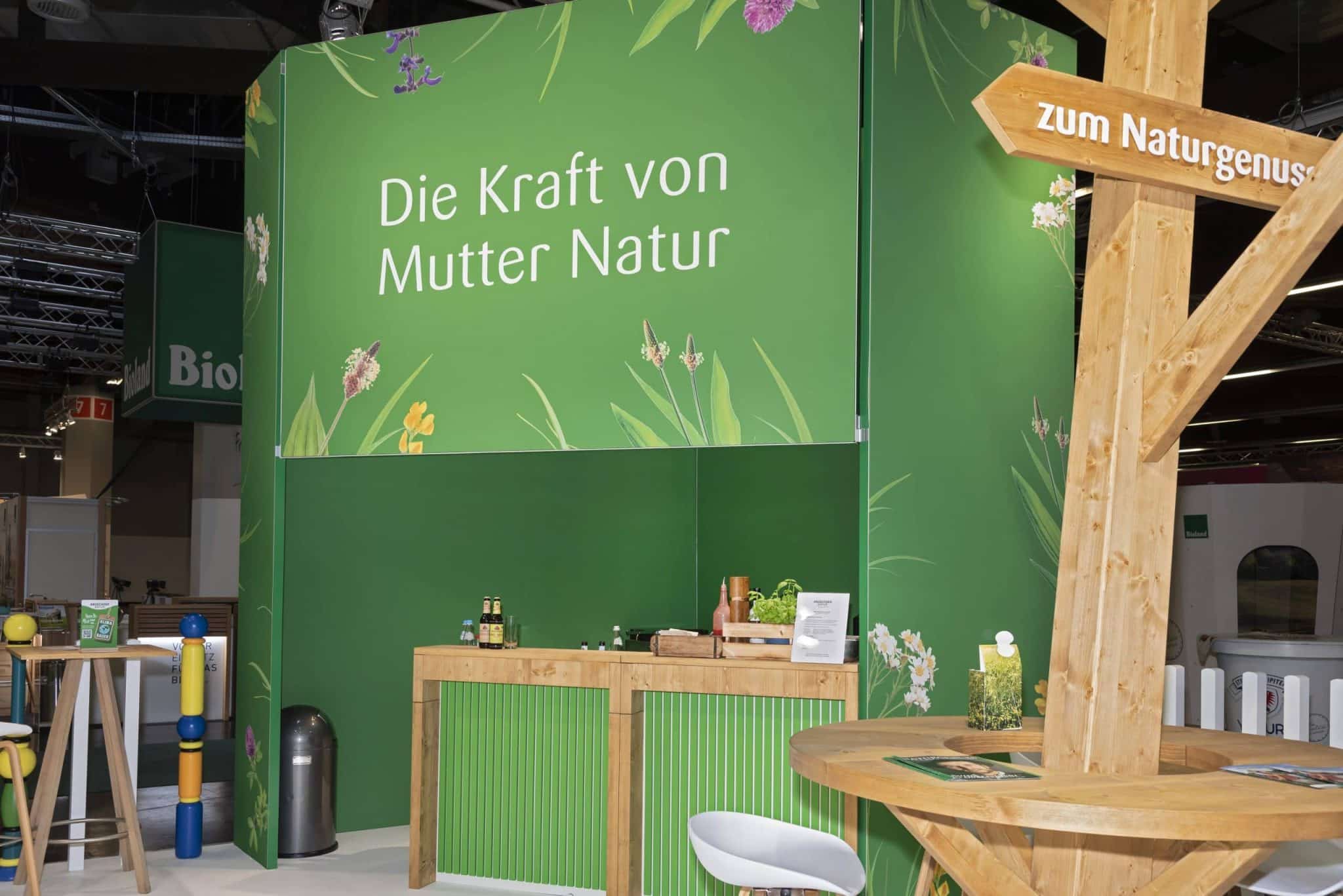 Rückseite des Andechser Natur Messestands mit der Aufschrift „Die Kraft von Mutter Natur“ auf der Biofach in Nürnberg – Messebau Nürnberg.
