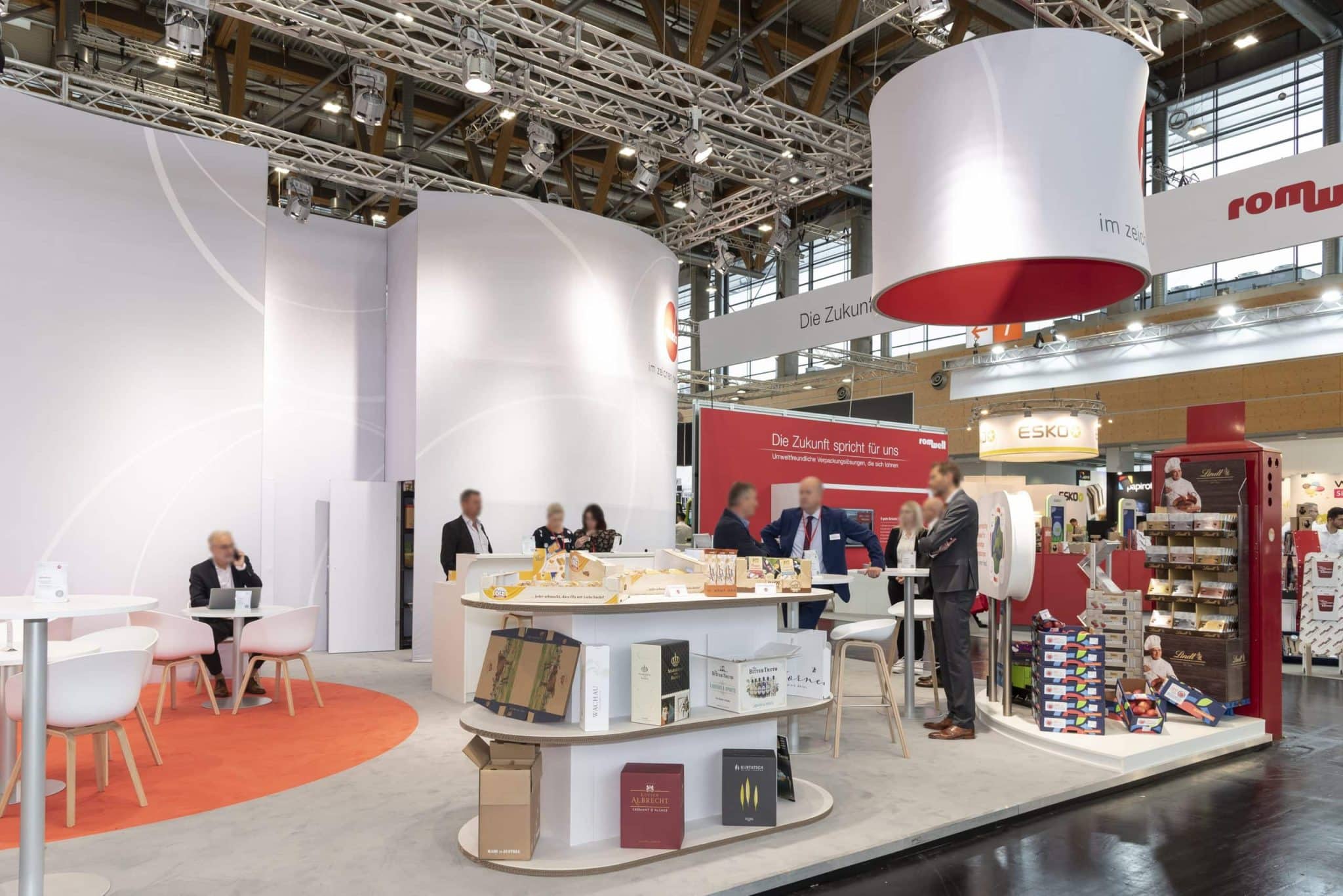 Besucher in Dirndl und Tracht am Abel Wiesn Messestand mit Holzhütte und Biertischen auf der Fachpack Nürnberg – Messebau Nürnberg.