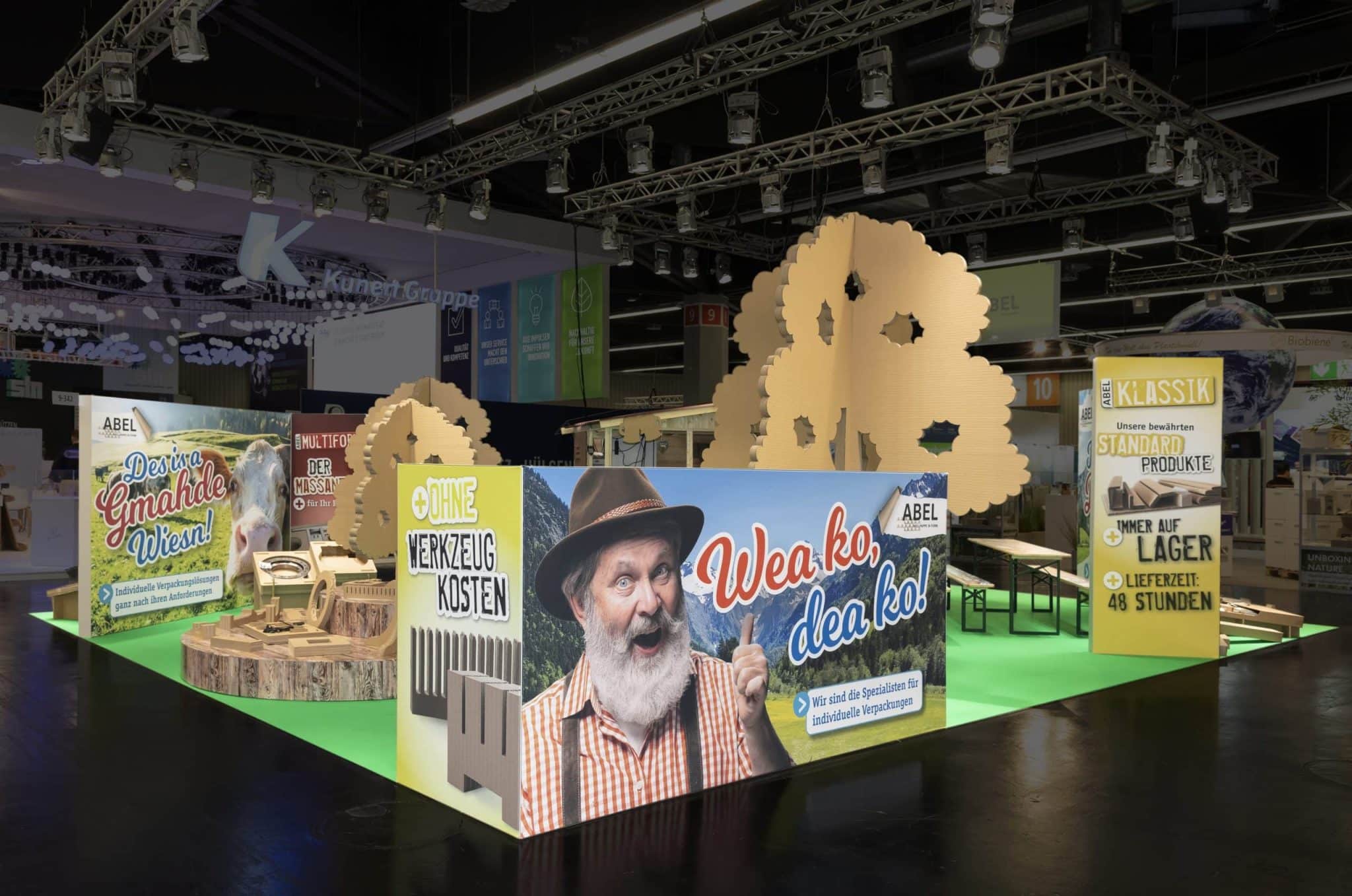 Rückseite des Abel Messestands mit auffälligem Werbebanner „Wea ko, dea ko“ auf der Fachpack Nürnberg – Messebau Nürnberg.