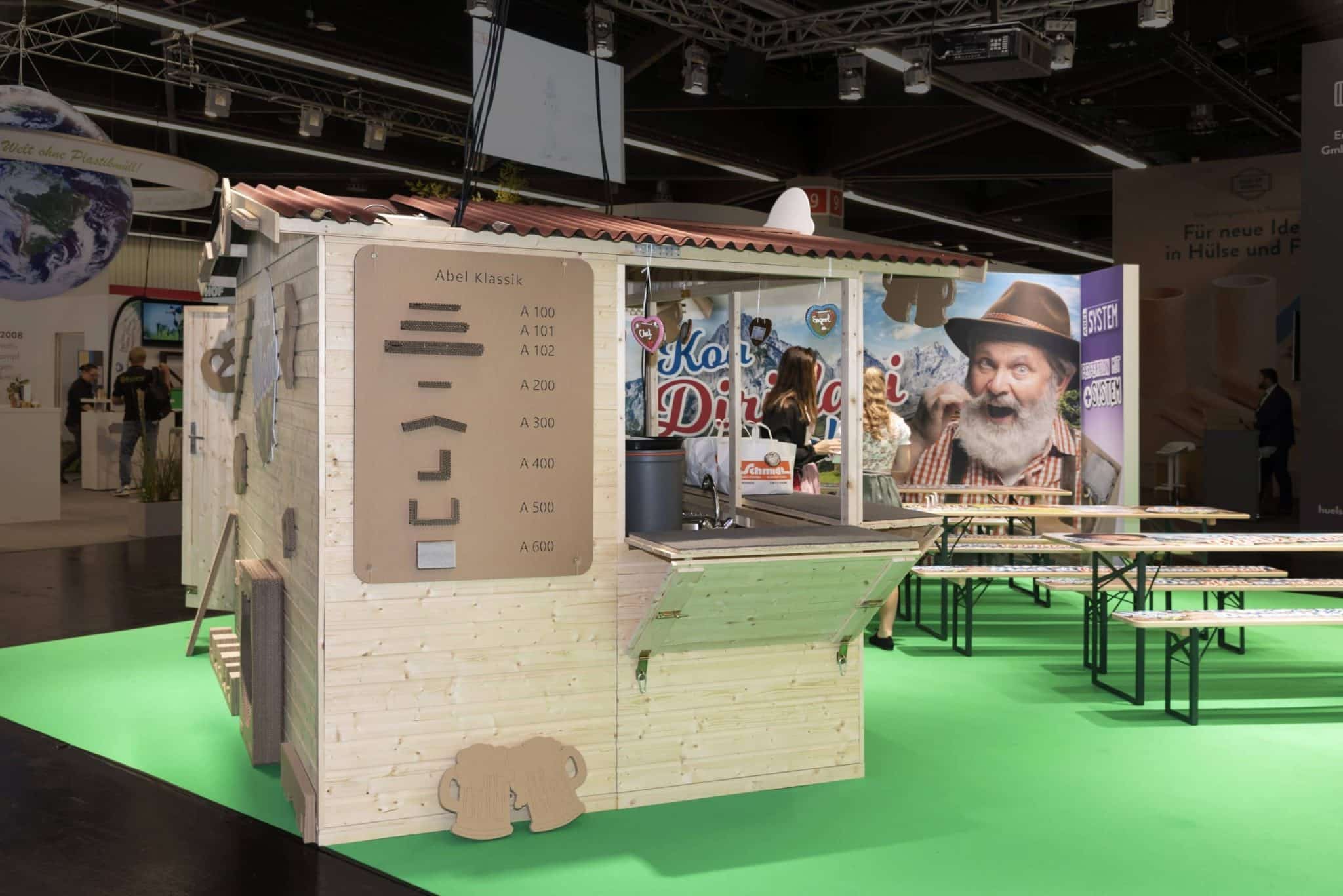 Rückseite des Abel Wiesn Messestands auf der Fachpack Nürnberg mit Produktübersicht „Abel Klassik“ – Messebau Nürnberg.