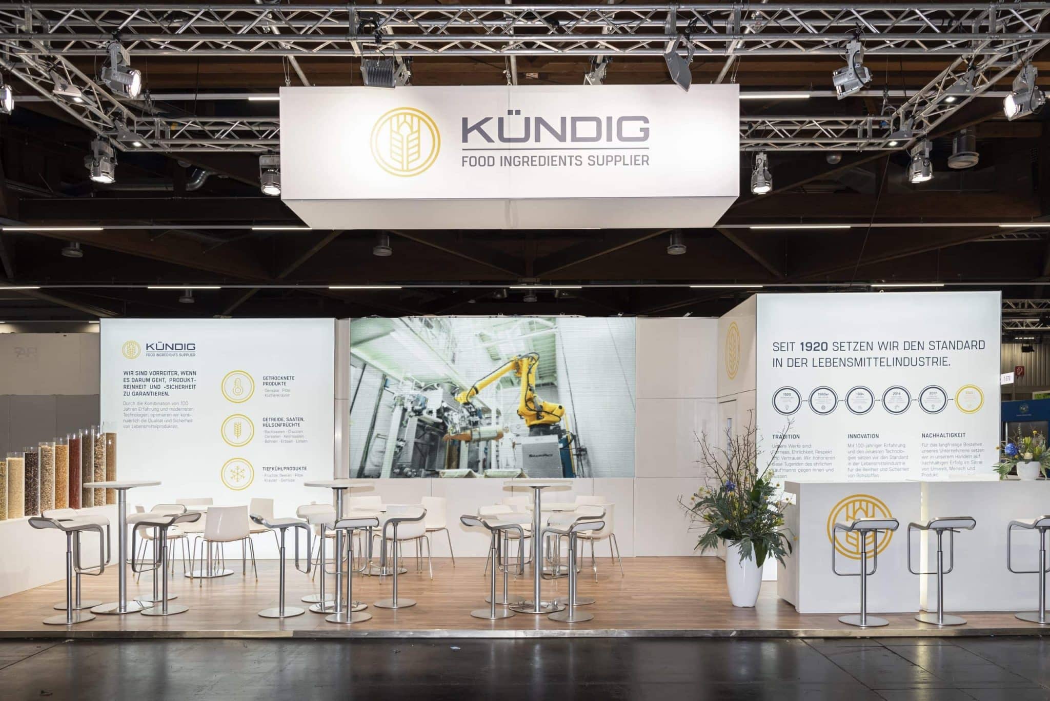 Heller Messestand von Kündig auf der Biofach 2025 in Nürnberg mit LED-Wand, Barbereich und Infotafeln.