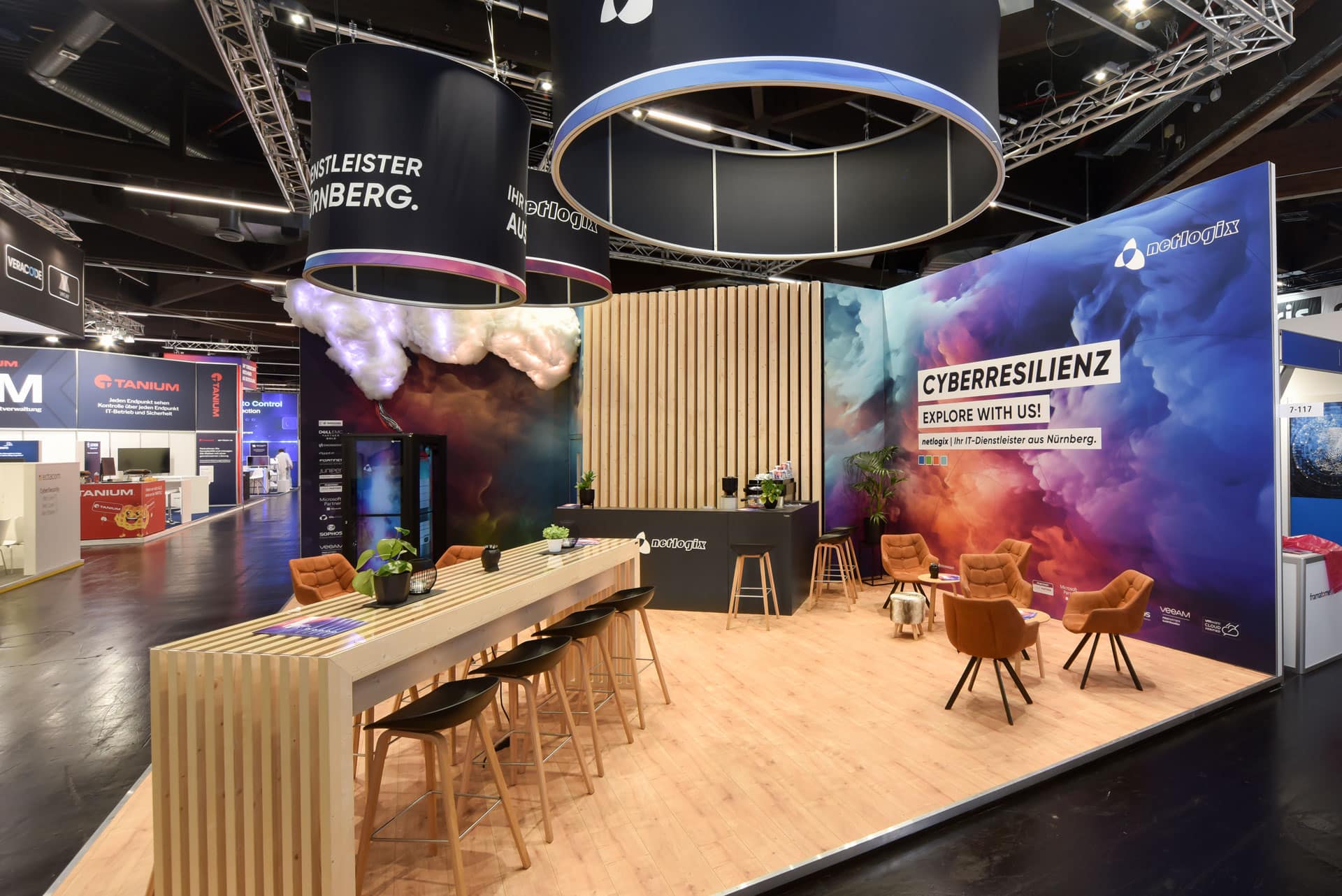 Seitenansicht des Medtech Live 2023 Messestands von Löew Präzisionsteile mit grüner Markenwand, Aluminiumteilen und beleuchteten Glasvitrinen.