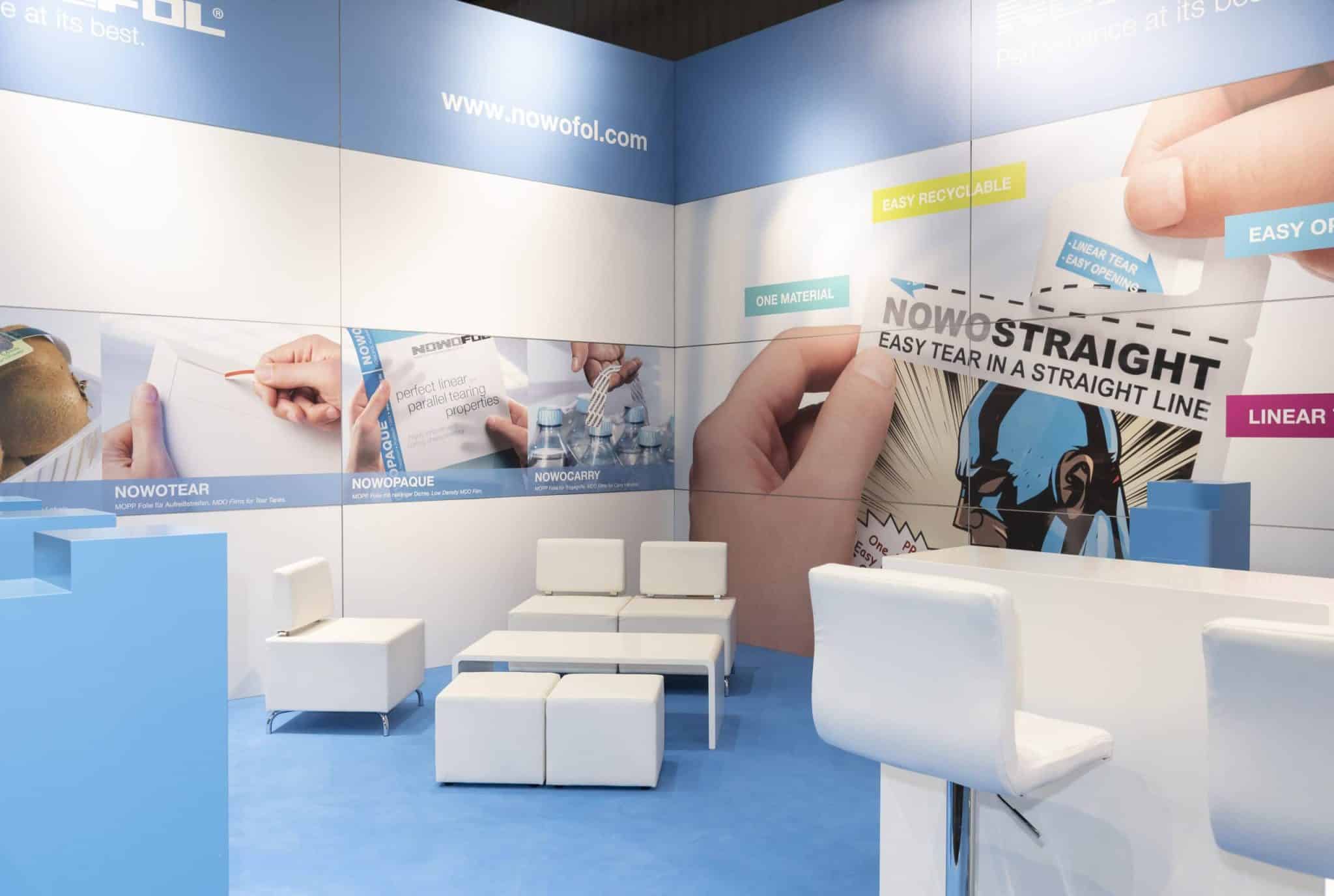 Moderner Messestand von Nowofol auf der Fachpack in Nürnberg mit Sitzmöbeln und Produktgrafiken „Messebau Nürnberg“.