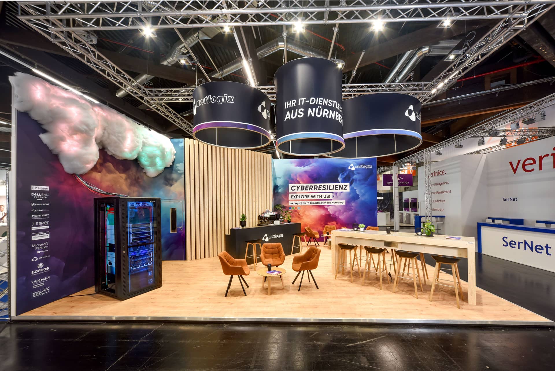 Frontansicht des Messestandes von Löew Präzisionsteile und Diener & Rapp auf der Medtech Live 2023 in Nürnberg mit rotem Popcornwagen und Glasvitrinen.