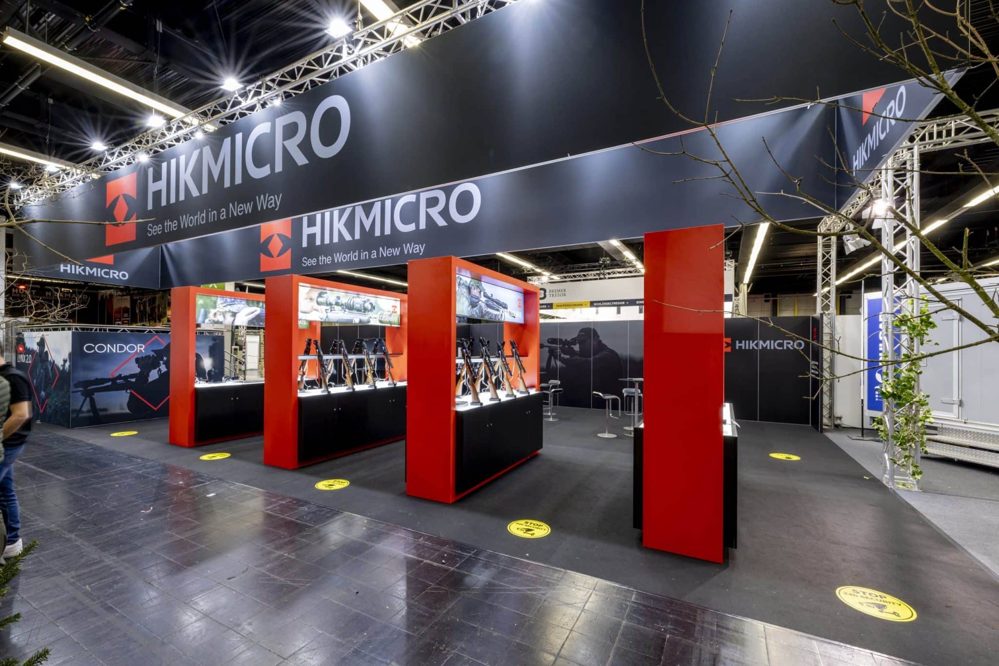 Hikmicro Messestand mit roten Produktinseln und Präsentation von Zielfernrohren – Messebau Dortmund