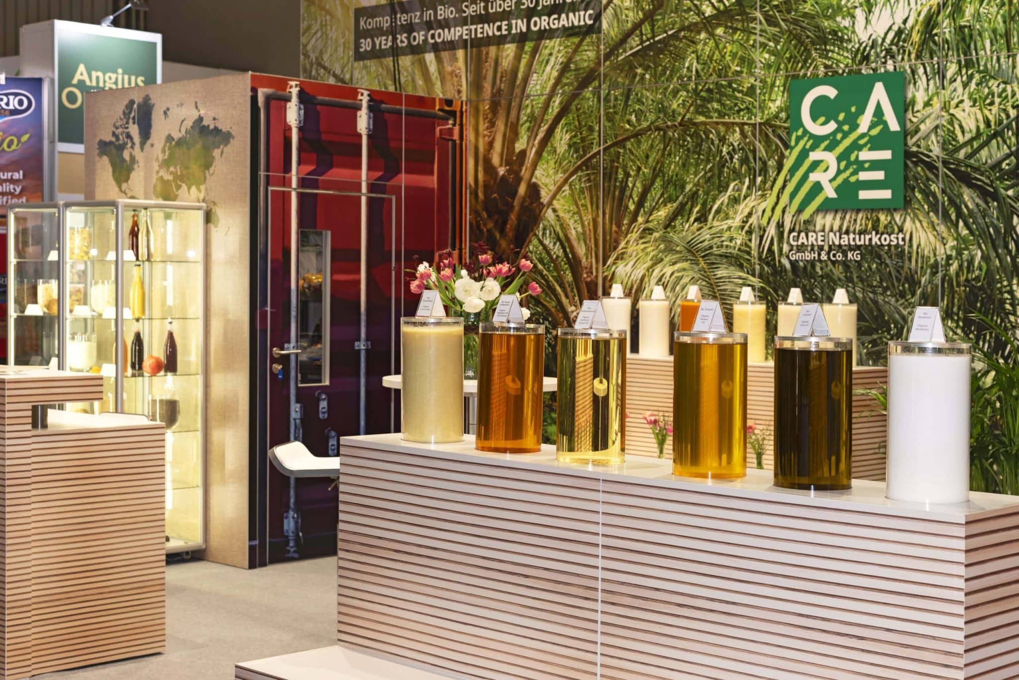 BioFach Nürnberg – CARE Naturkost Messestand mit Produkten in Glaszylindern, umgesetzt durch hochwertigen Messebau Nürnberg.