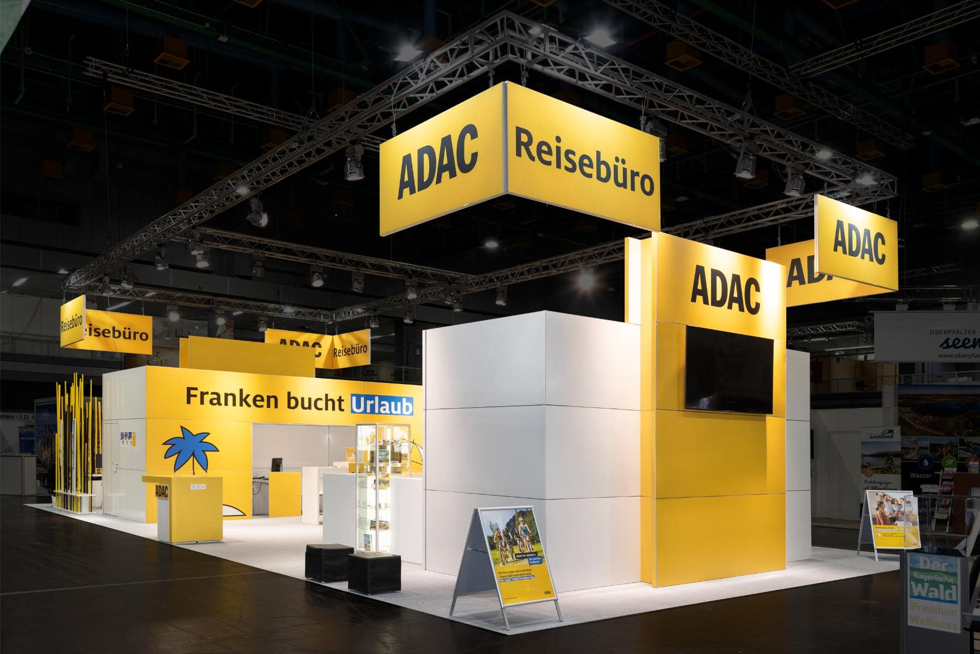 ADAC Messestand mit großem Reisebüro-Bereich, Infotafeln und auffälligem Gelb-Weiß-Design auf der Freizeitmesse Nürnberg 2024.