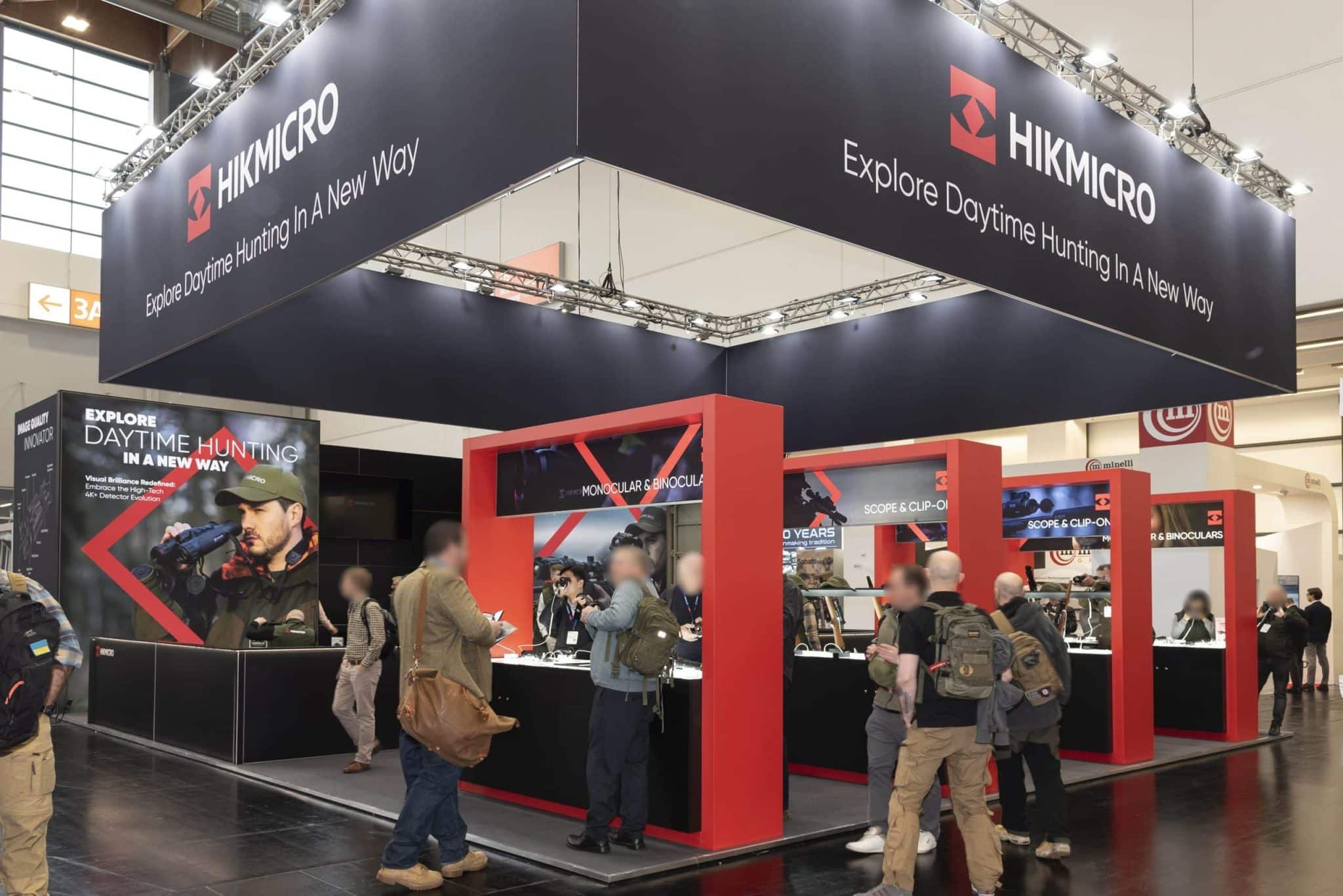 Messestand von HIKMICRO auf der Jagd & Hund Messe in Dortmund – moderner Messebau Dortmund mit großem Deckenbanner, roten Produktinseln und Besuchern im Gespräch.