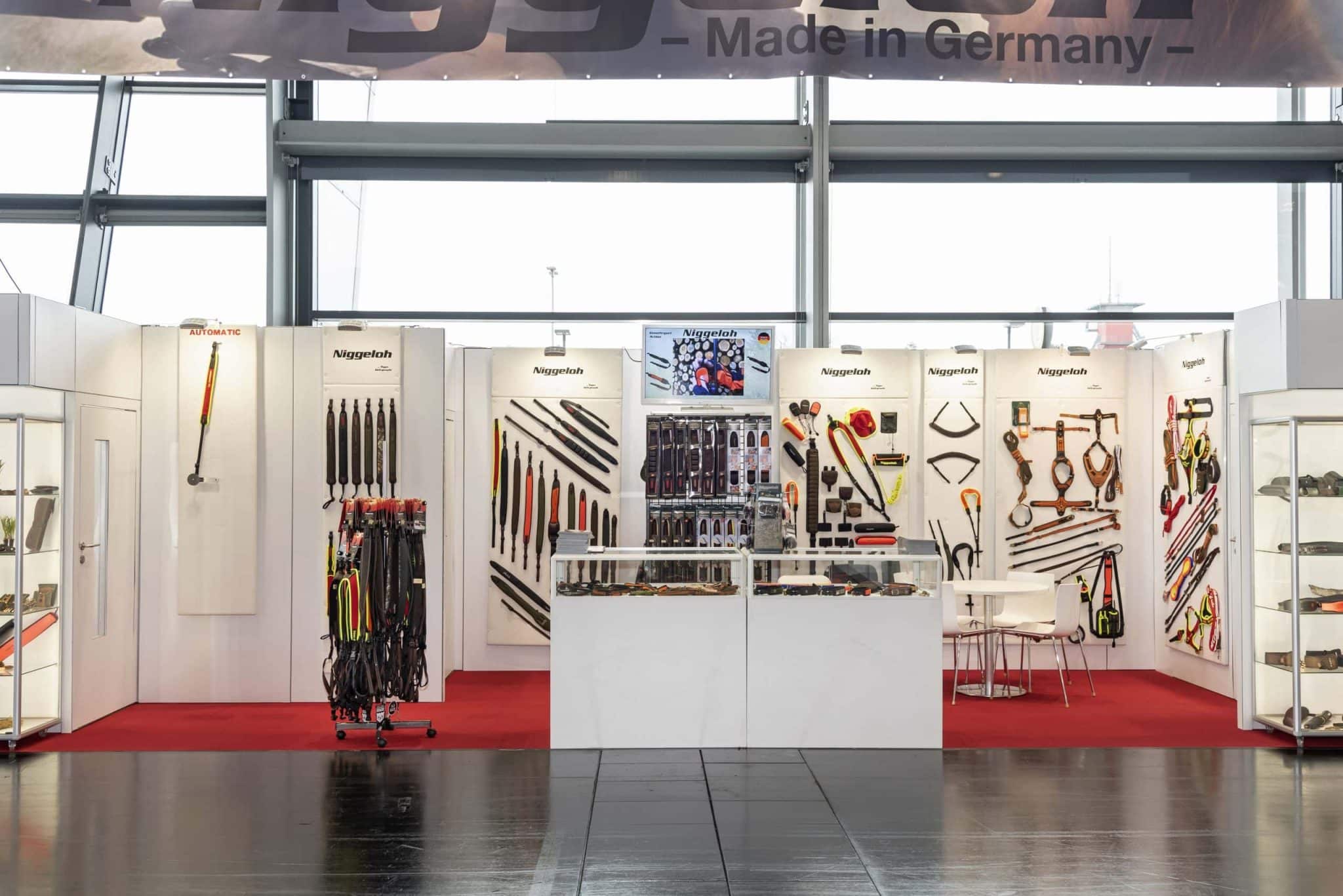 Messestand von Niggeloh auf der IWA Nürnberg mit Produktpräsentationen, weißen Wänden und rotem Teppich – Messebau Nürnberg