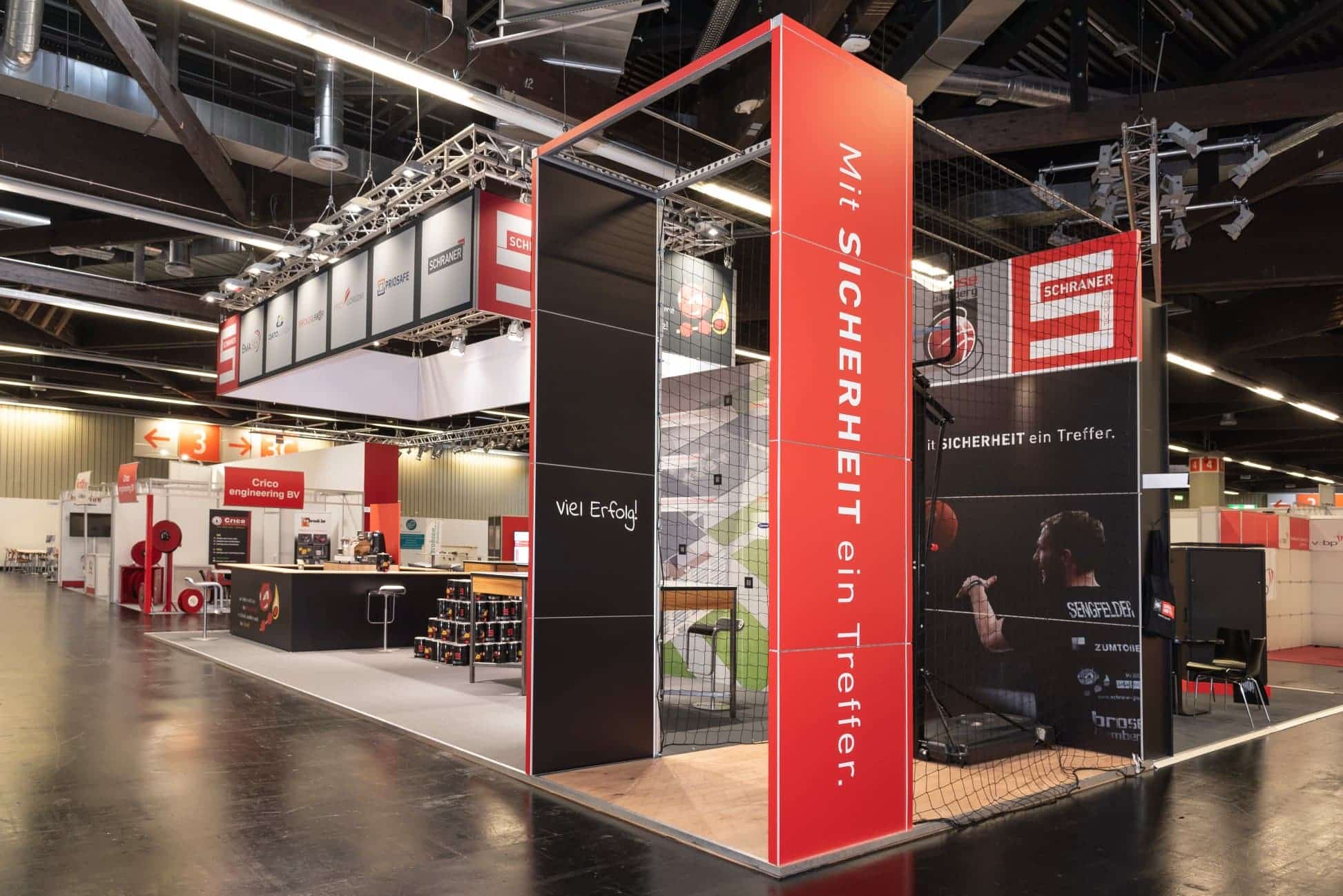 Moderner Messestand von Schraner Group auf der FeuerTrutz in Nürnberg mit Basketballkorb und rotem Sicherheitsslogan.