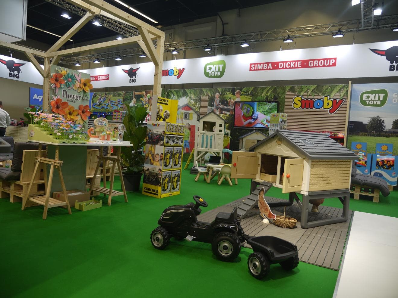 Detailansicht des Messestandes mit Spielzeugtraktor, Hühnerhaus und Flower-Market-Dekoration von EXIT Toys und Smoby.