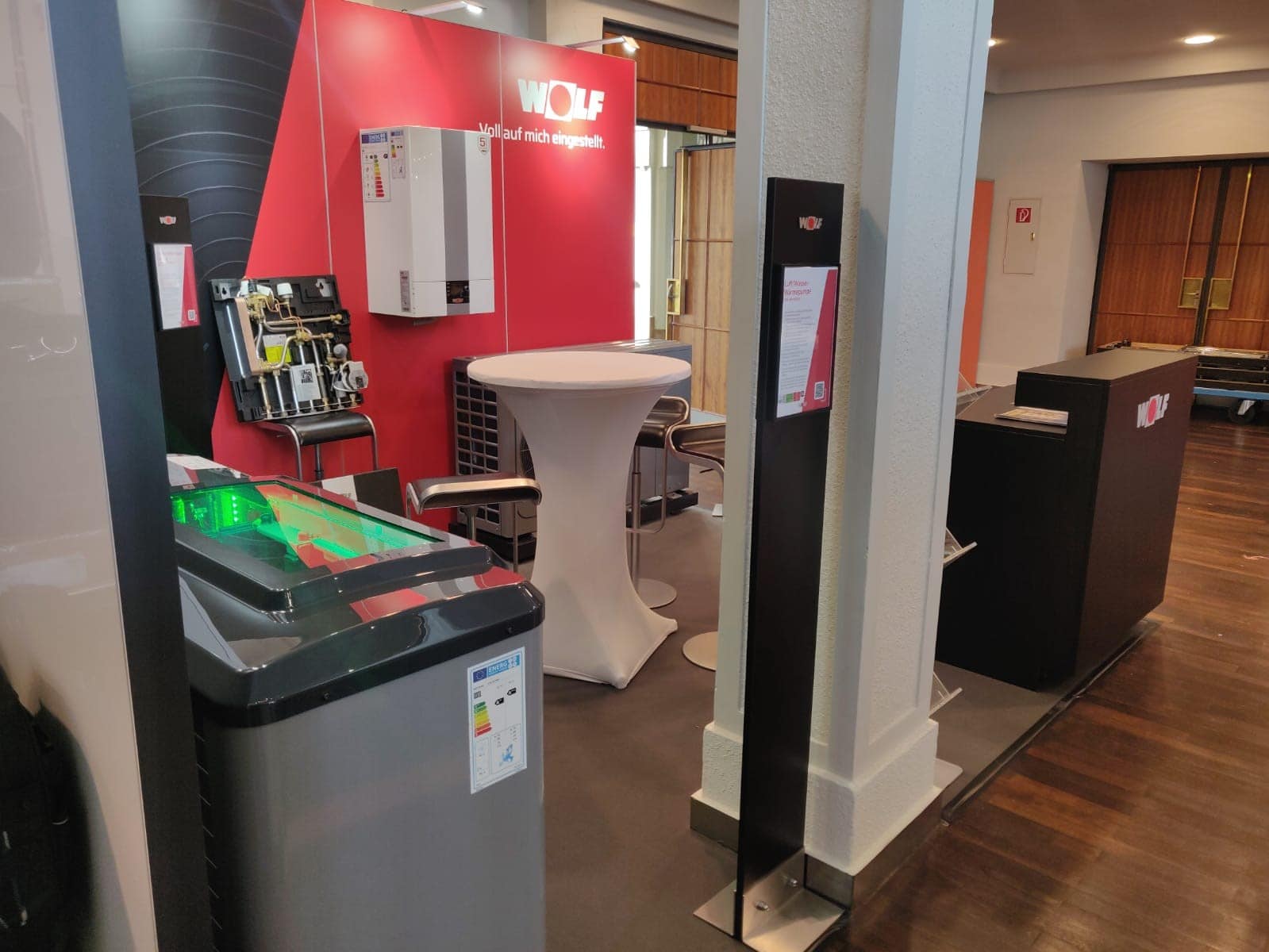 WOLF Messestand mit Wärmepumpe, Heizsystem und Stehtisch auf der Sanitärmesse Ufer in Landau – energieeffiziente Lösungen, Messebau Landau.