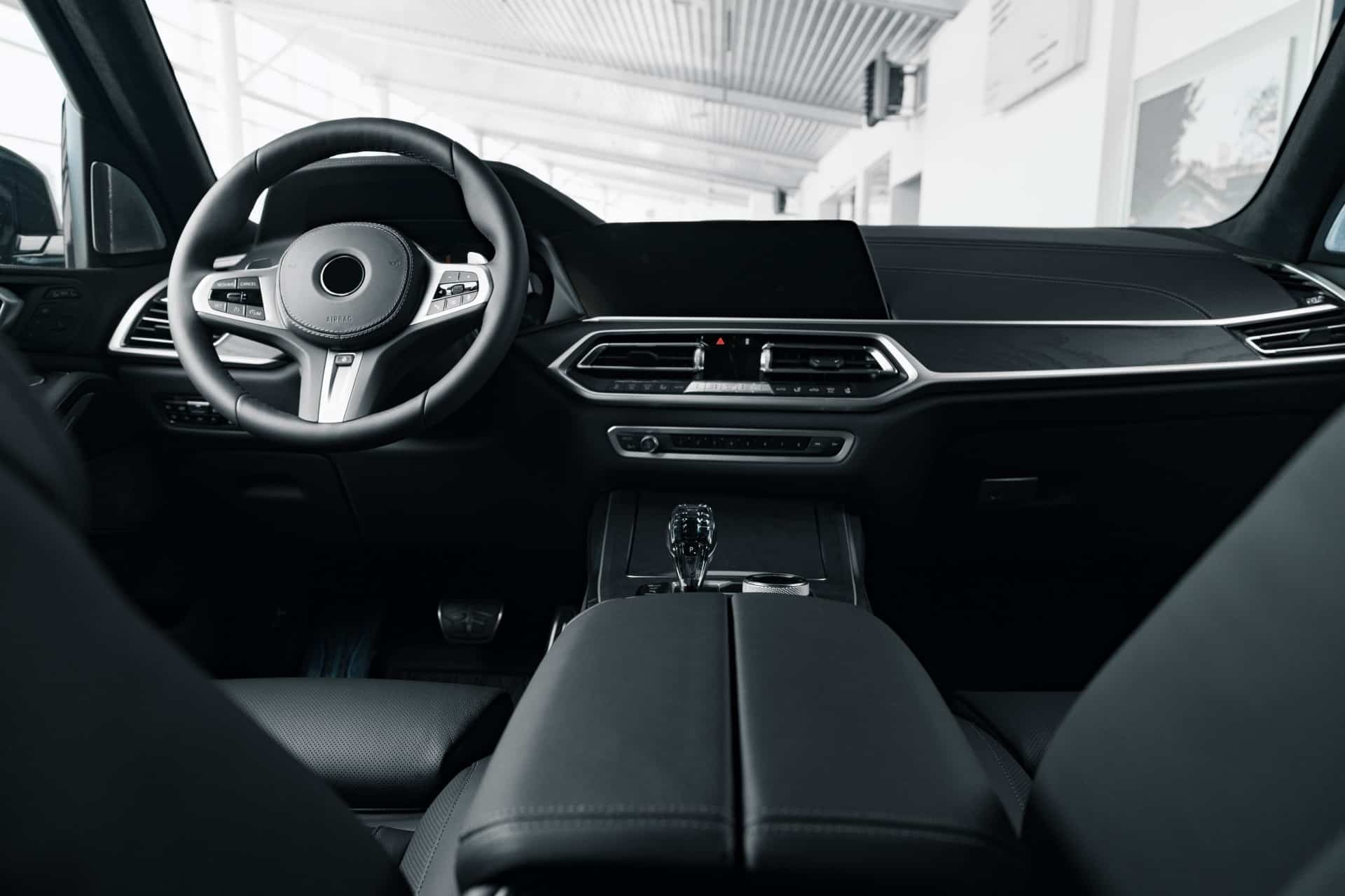 Innenansicht eines modernen Autos mit elegantem Armaturenbrett und digitalem Display, das an IAA-Innovationen erinnert, zentralem Bedienfeld und Lenkrad. Das Design zeichnet sich durch schwarze und metallische Akzente aus und vermittelt eine anspruchsvolle, minimalistische Ästhetik.