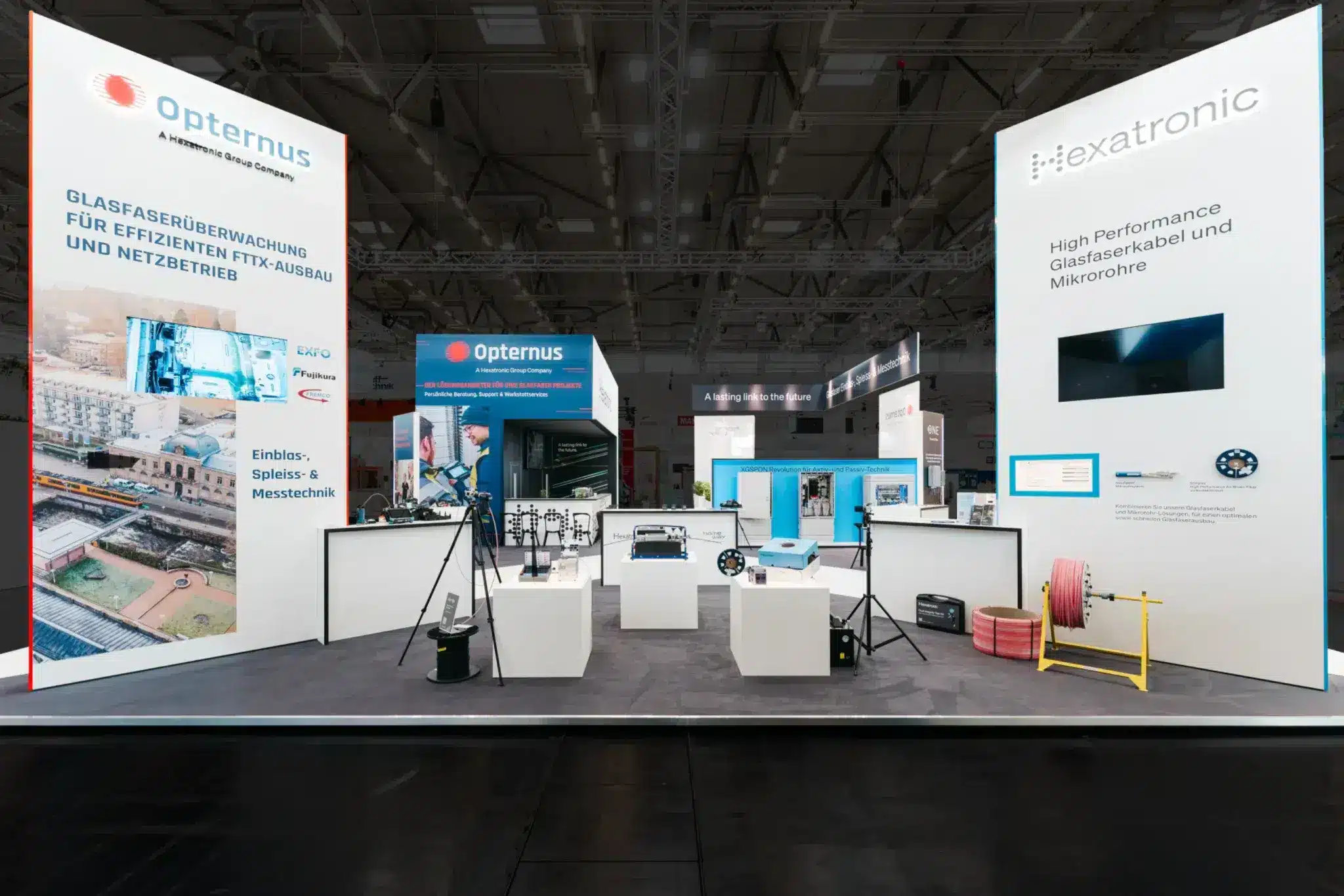 Messebau Köln – moderner Messestand von Opternus und Hexatronic mit Glasfaserkabel und Netzwerktechnik.