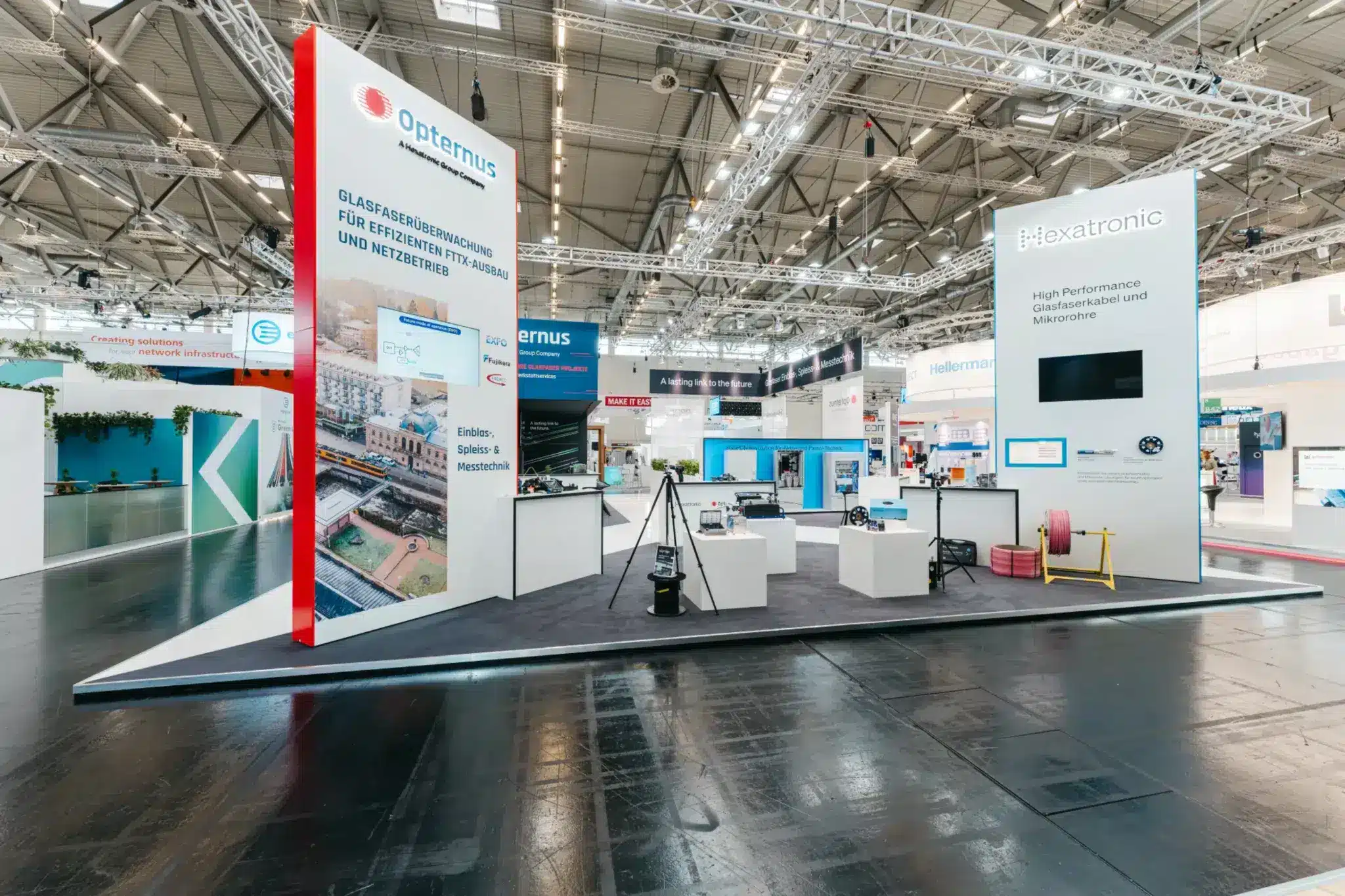 Vorderseite des Opternus Bereichs mit Präsentation für Glasfaserüberwachung und Technik-Exponaten, modern gestaltet.