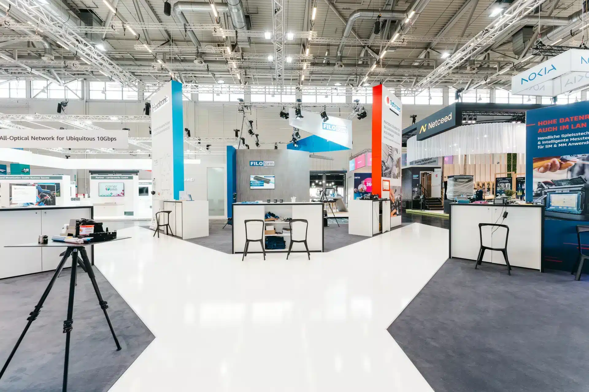 Blick auf den Messestand von Hexatronic mit offenen Präsentationsflächen und weißen Möbeln.