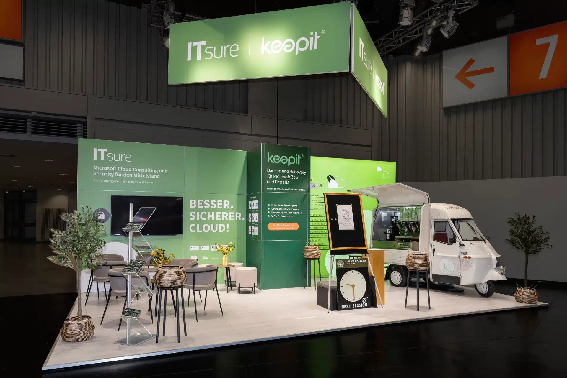 ITsure | Keepit Messestand auf der it-sa 2024 mit großem grünen Banner und Coffee Car als Blickfang.