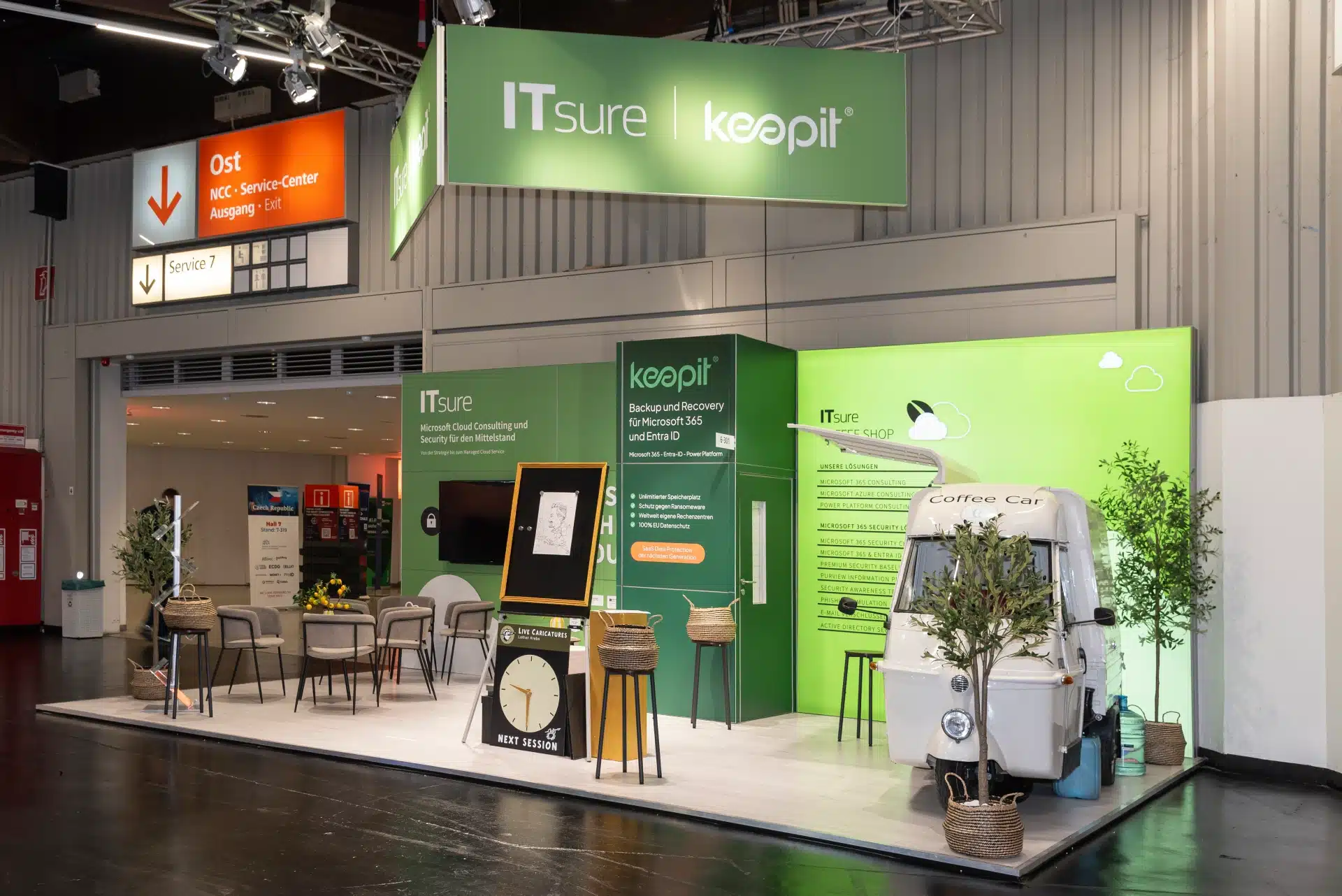 Messestand von ITsure und Keepit mit Coffee Car, Lounge-Bereich und grünem Branding auf der it-sa 2024 in Nürnberg.
