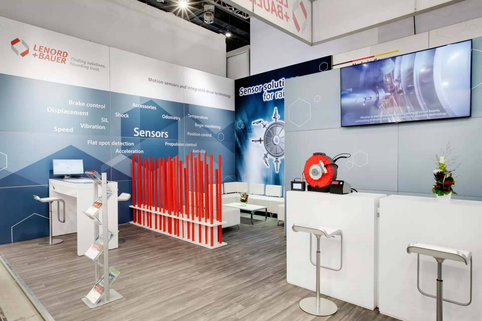 Detailansicht mit roter Stangeninstallation, Infotheke und Präsentation der Sensorsysteme von Lenord + Bauer.