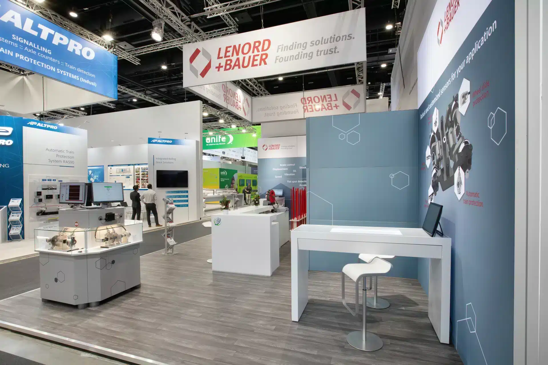 Moderner Messestand von Lenord + Bauer auf der InnoTrans 2024 in Berlin mit Infotheke, Vitrine und Wandgrafiken zu Sensortechnologien.