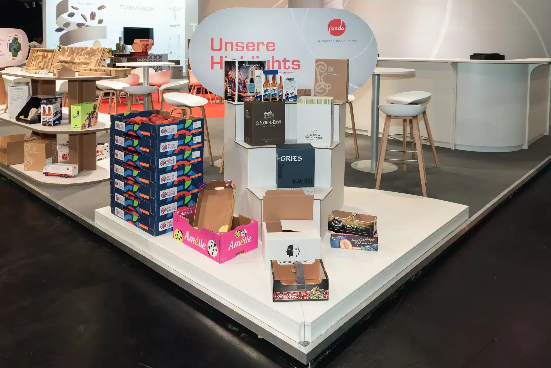 Nahaufnahme der Rondo Ausstellungsfläche auf der Fachpack 2024 mit gestapelten Obst- und Getränkekartons „Unsere Highlights“ – Messebau Nürnberg.