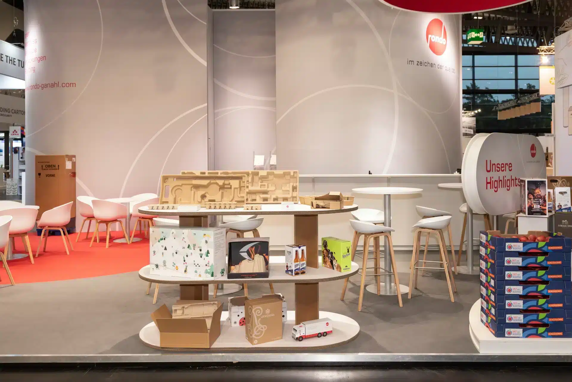 Präsentationsbereich des Rondo Standes auf der Fachpack 2024 mit Regalen voller nachhaltiger Verpackungsmuster – Messebau Nürnberg.