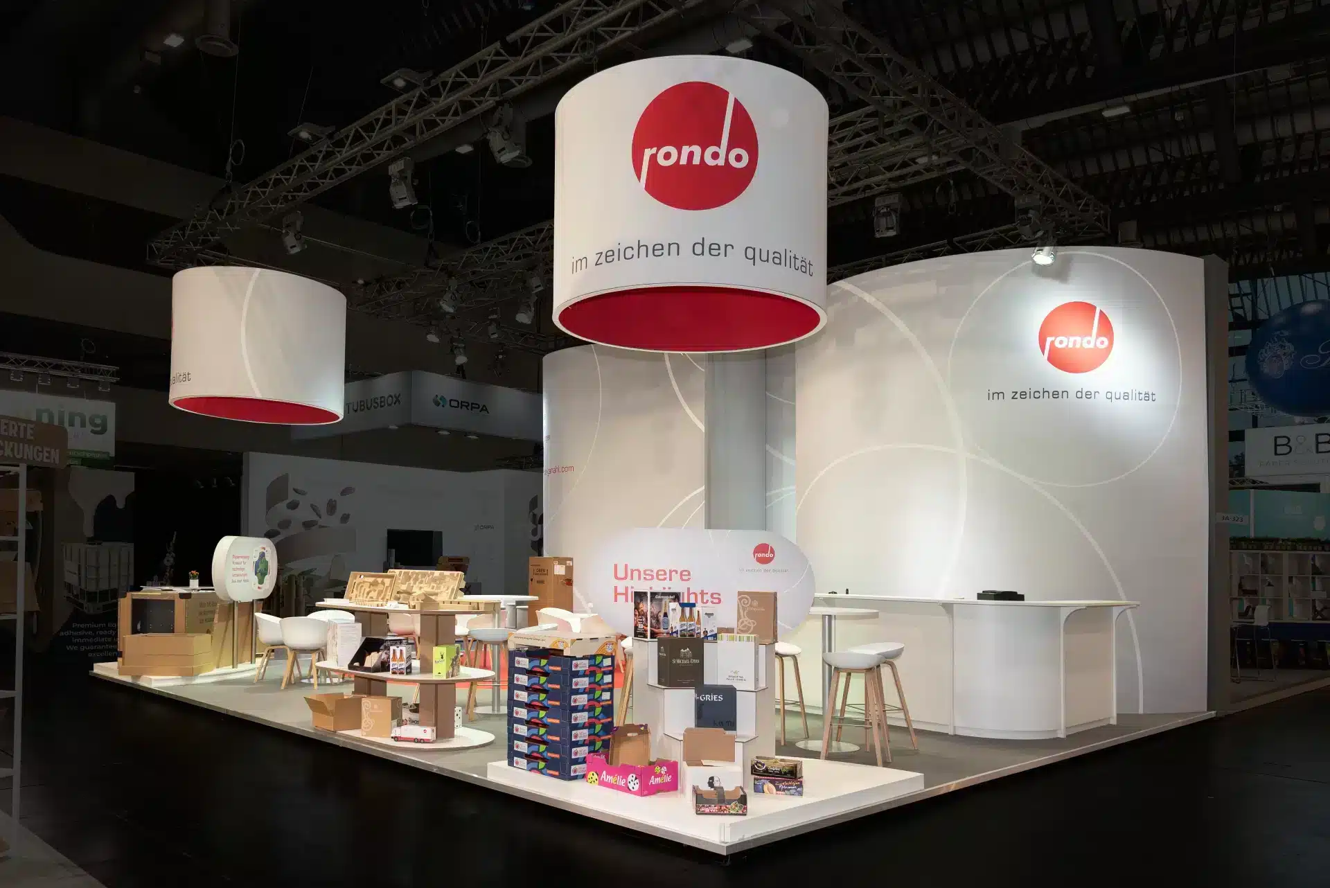 Moderner Rondo Messestand auf der Fachpack 2024 mit weißen Wänden, roten Deckenelementen und nachhaltigen Verpackungslösungen – Messebau Nürnberg.