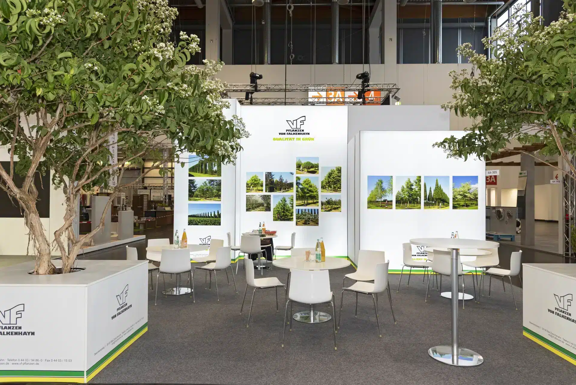 Messebau Nürnberg – Grüner Messestand mit Sitzplätzen und großem Baum, GalaBau Ausstellung.