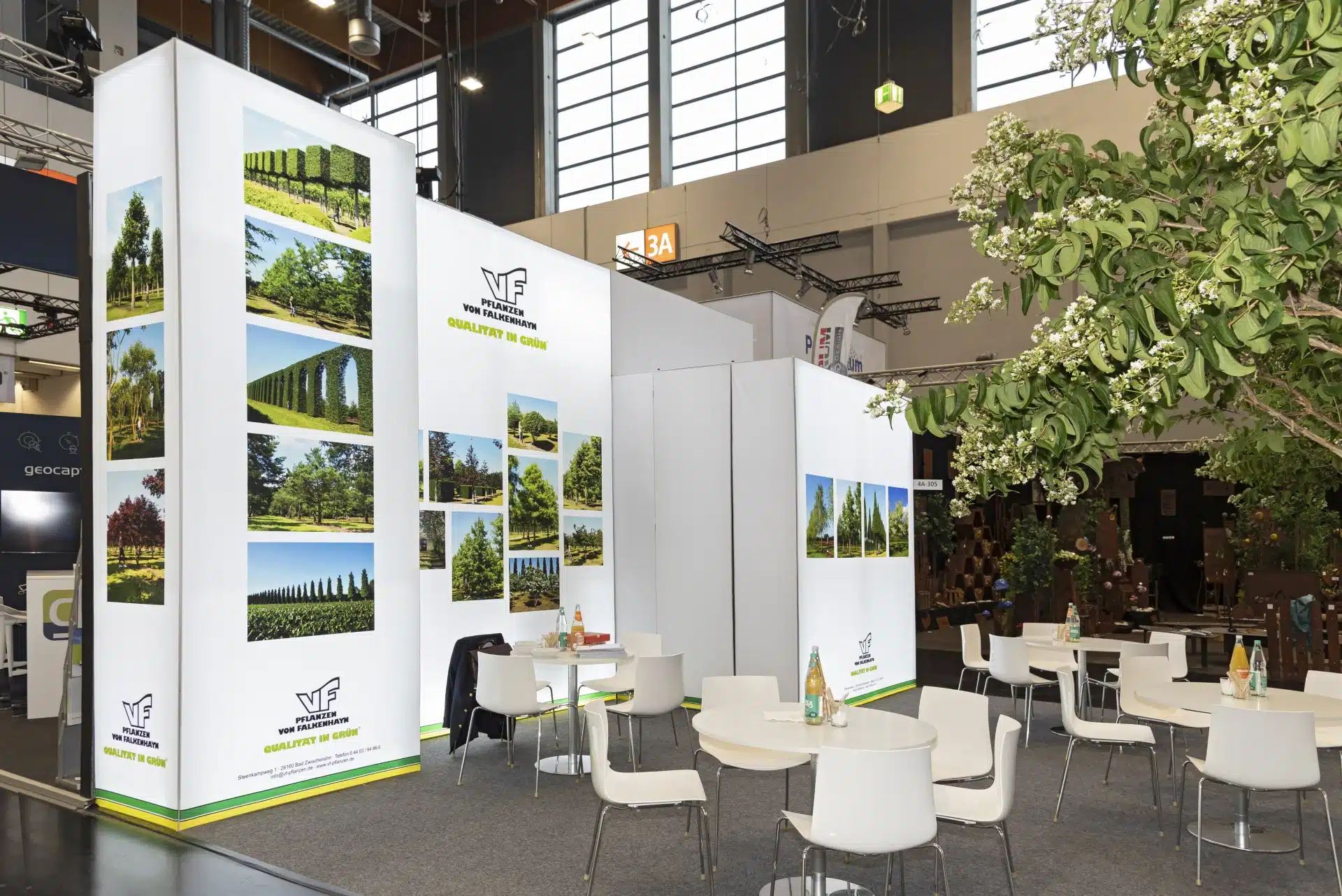 Messebau Nürnberg – Weißer Messestand mit großflächigen Baumfotos und Sitzbereich auf der GalaBau.