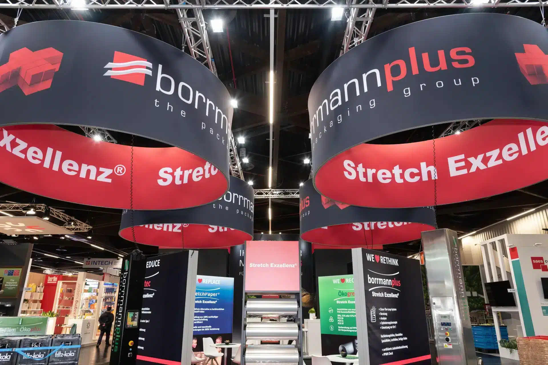 Blick nach oben auf die großen Ringbanner „Stretch Exzellenz®“ über dem Stand von Borrmann Plus, Messebau Nürnberg