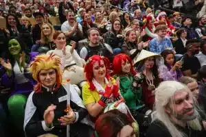 Eine lebhafte Menschenmenge füllt den Saal des Stuttgarter MesseHerbst, viele in farbenfrohen und aufwendigen Cosplay-Kostümen. Lächelnd und klatschend genießt die Gruppe die Veranstaltung und sorgt für eine lebendige und energiegeladene Atmosphäre.