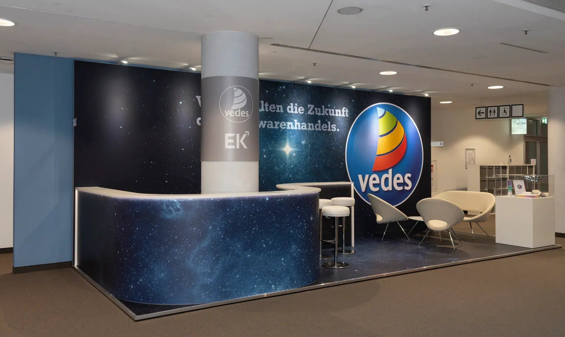 Messebau Nürnberg – moderner Vedes Messestand auf der Spielwarenmesse 2025 mit Empfangstheke, Sternenhimmel-Design und Lounge-Bereich.