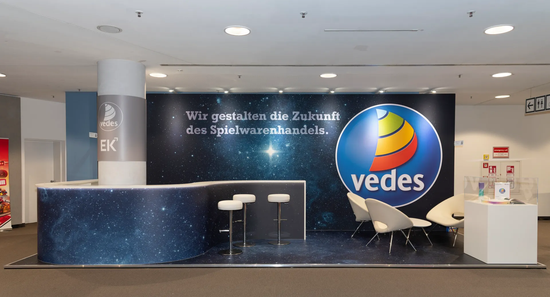 Messebau Nürnberg – Vedes Messestand mit großem Firmenlogo und Slogan „Wir gestalten die Zukunft des Spielwarenhandels“ auf der Spielwarenmesse 2025.