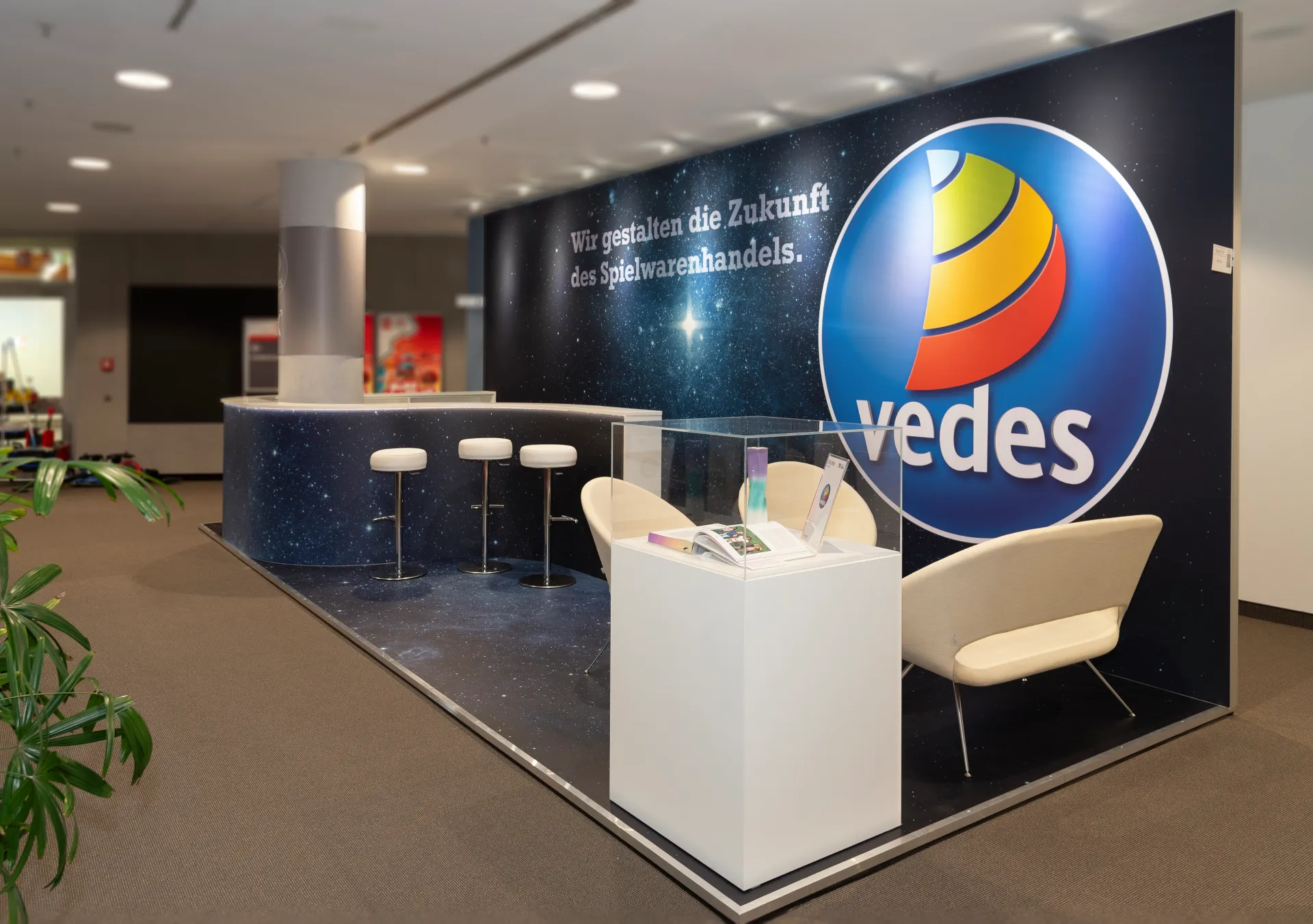 Messebau Nürnberg – offener Messestand von Vedes mit Sitzgelegenheiten und Empfangstheke im Sternendesign auf der Spielwarenmesse 2025.