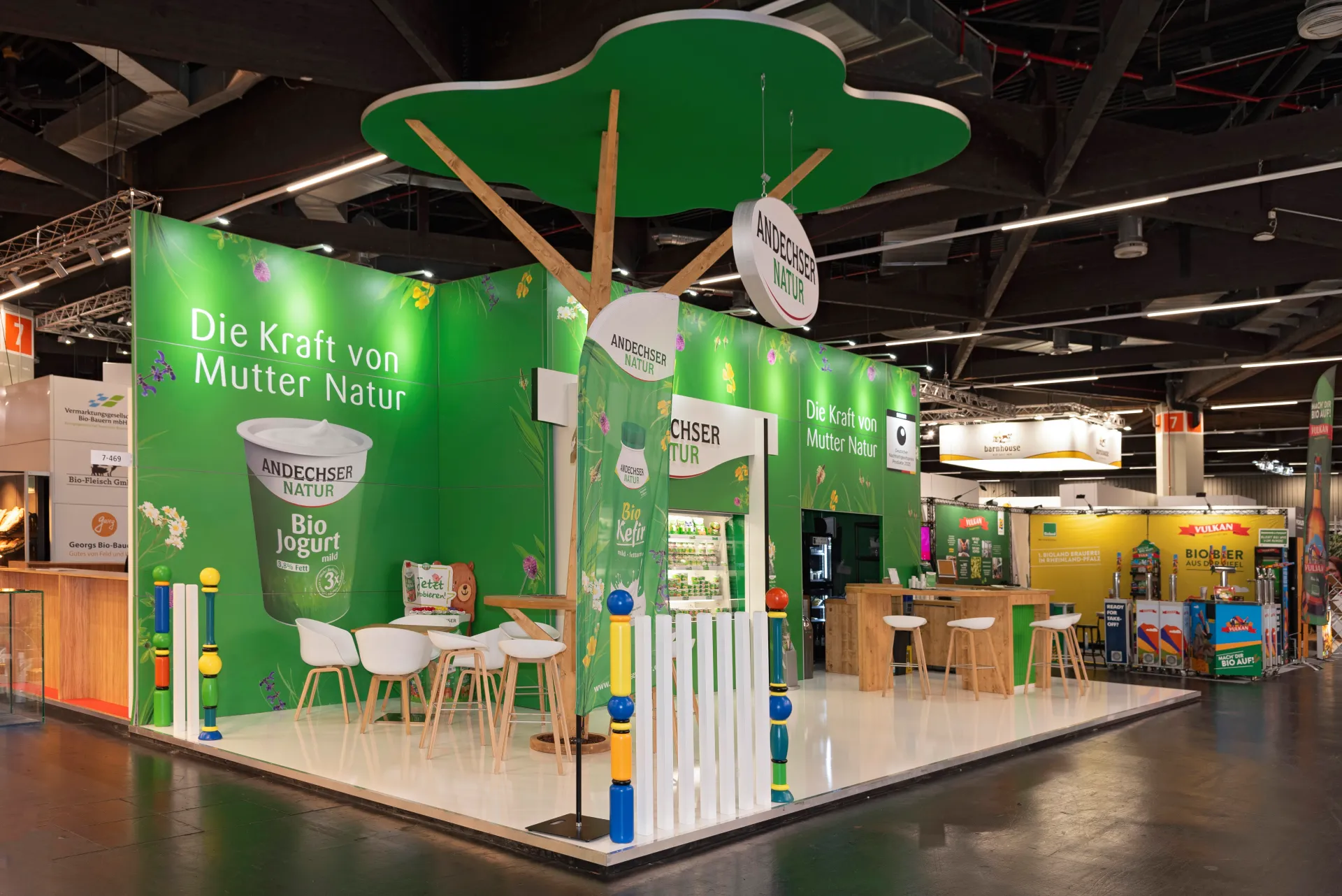 Offene Standseite von Andechser Natur mit Kinderbereich, Bio-Kefir-Werbung und grünem Messestand auf der BioFach Messe 2025 in Nürnberg.
