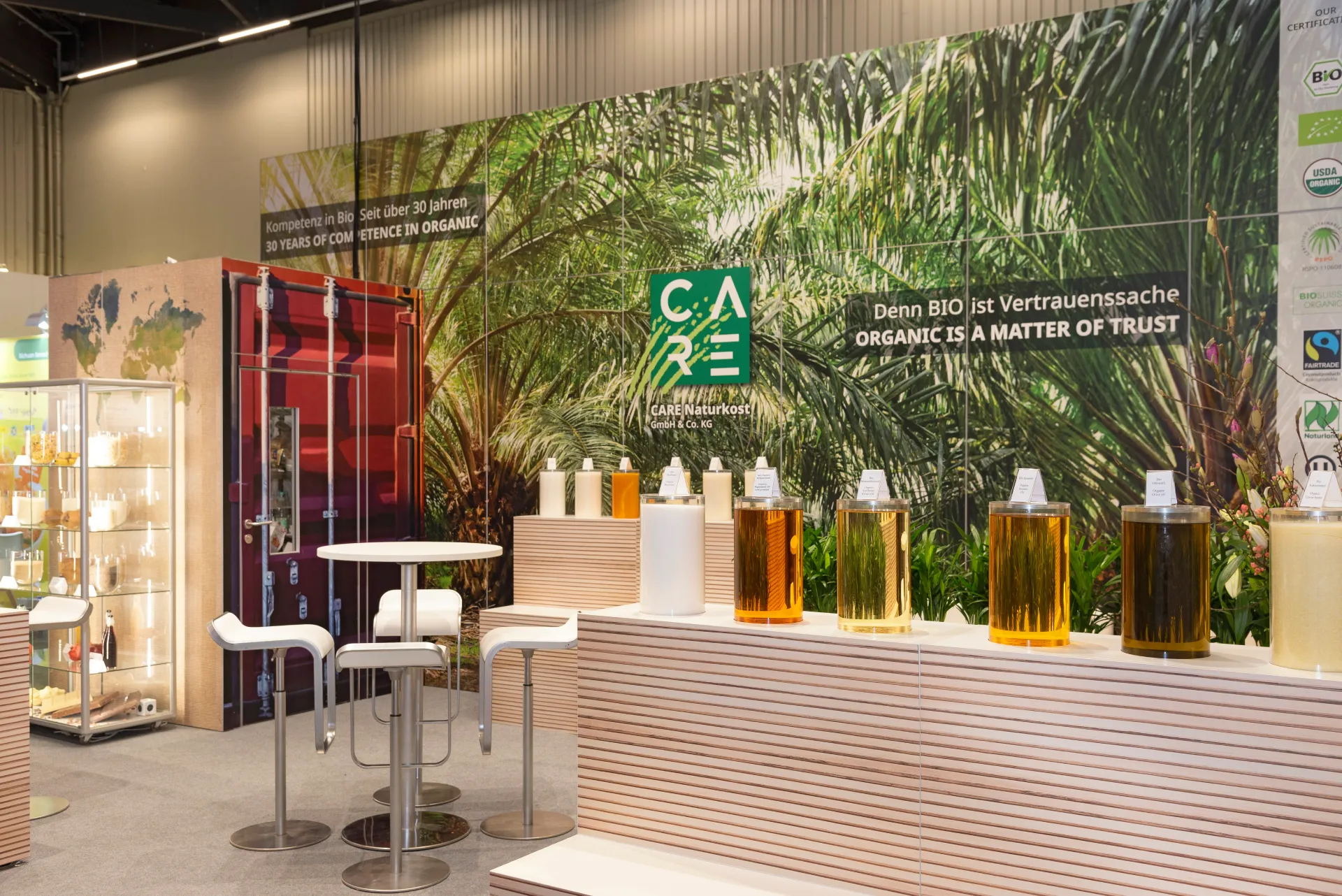 Moderner Messestand von CARE Naturkost mit Palmenmotiv und organischen Ölen auf der Biofach Messe 2025 in Nürnberg – Messebau Nürnberg.