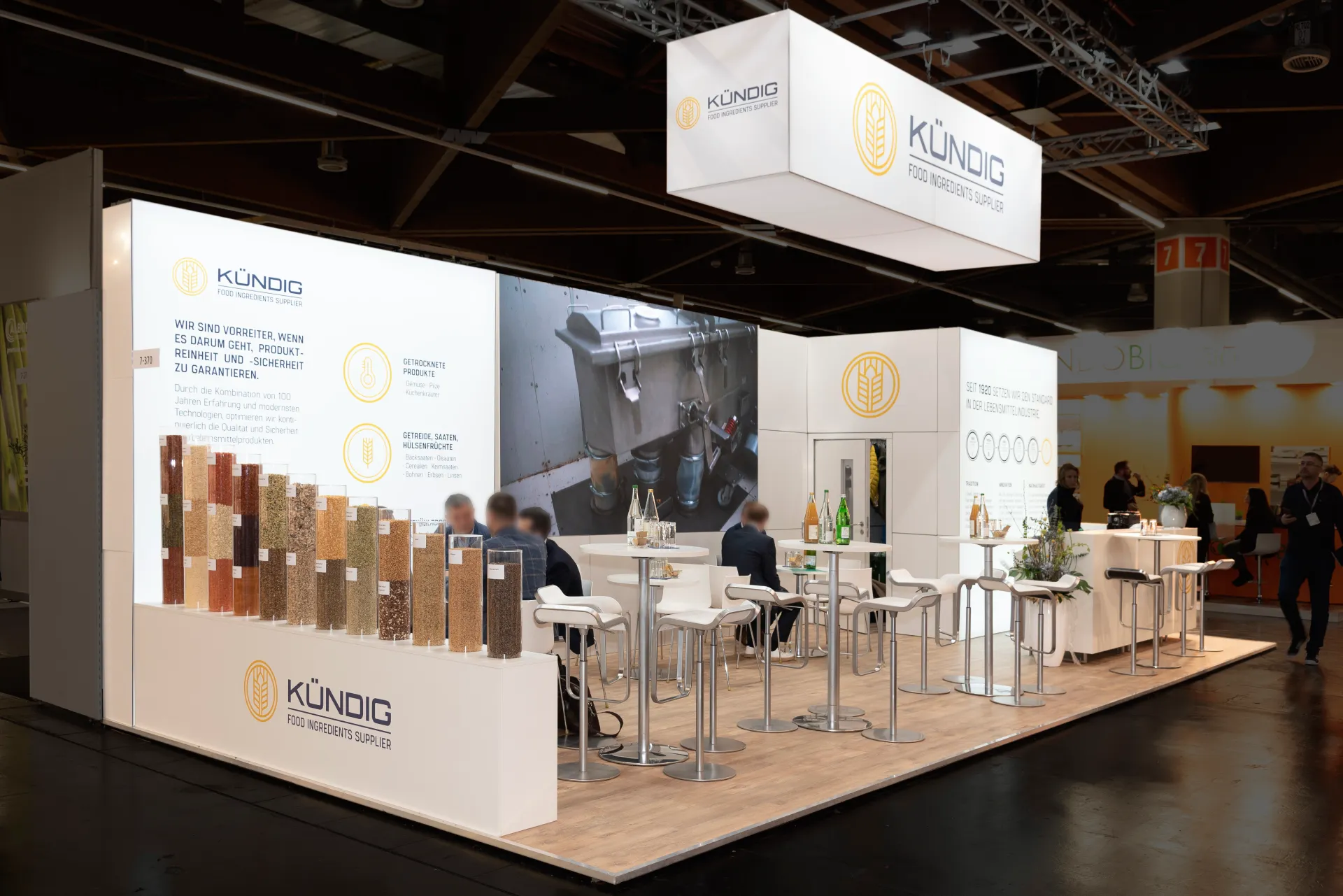 Offener Messestand von Kündig mit großer LED-Wand, Theke und Sitzbereich auf der Biofach 2025 in Nürnberg.