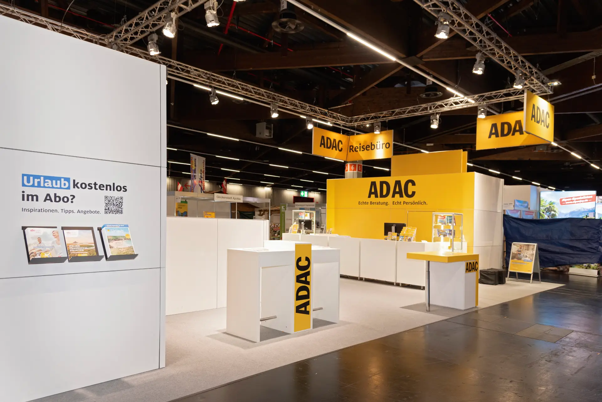 ADAC Reisebüro Messestand mit Prospektwand und Beratungstischen auf der Freizeit Touristik & Garten 2025 in Nürnberg.