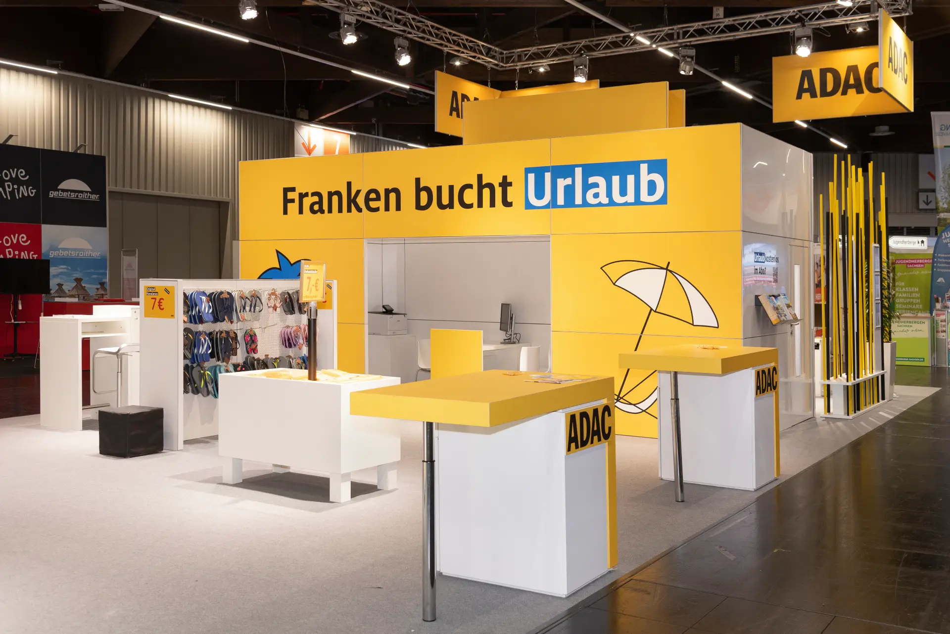 Moderner Messestand des ADAC auf der Freizeit Touristik & Garten 2025 in Nürnberg – gelb-weißer Stand mit Urlaubsthema und Reiseberatung.