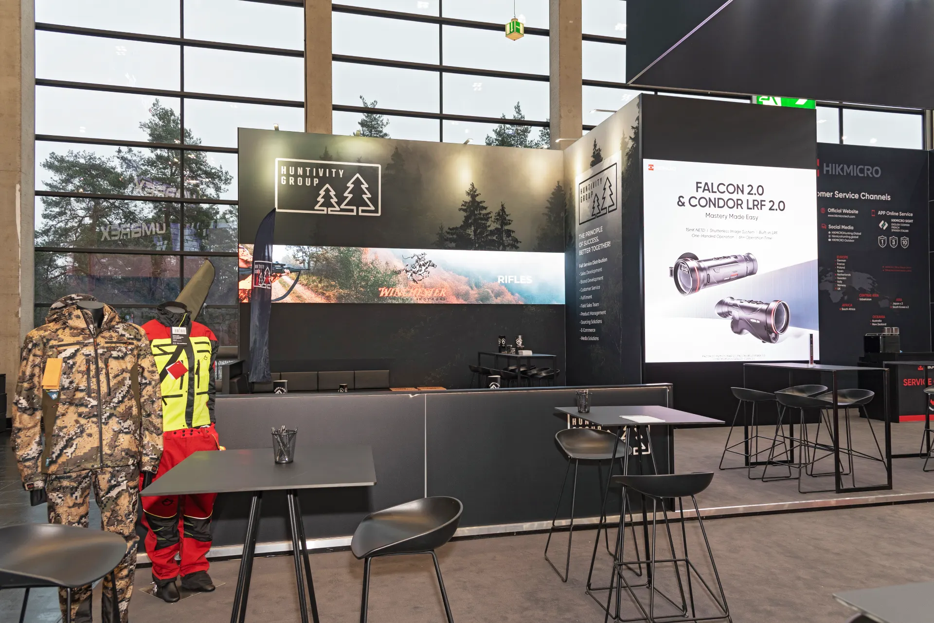 Präsentationsbereich der Huntivity Group mit ausgestellten Outdoor-Bekleidungen und großem LED-Screen – Messebau Nürnberg.