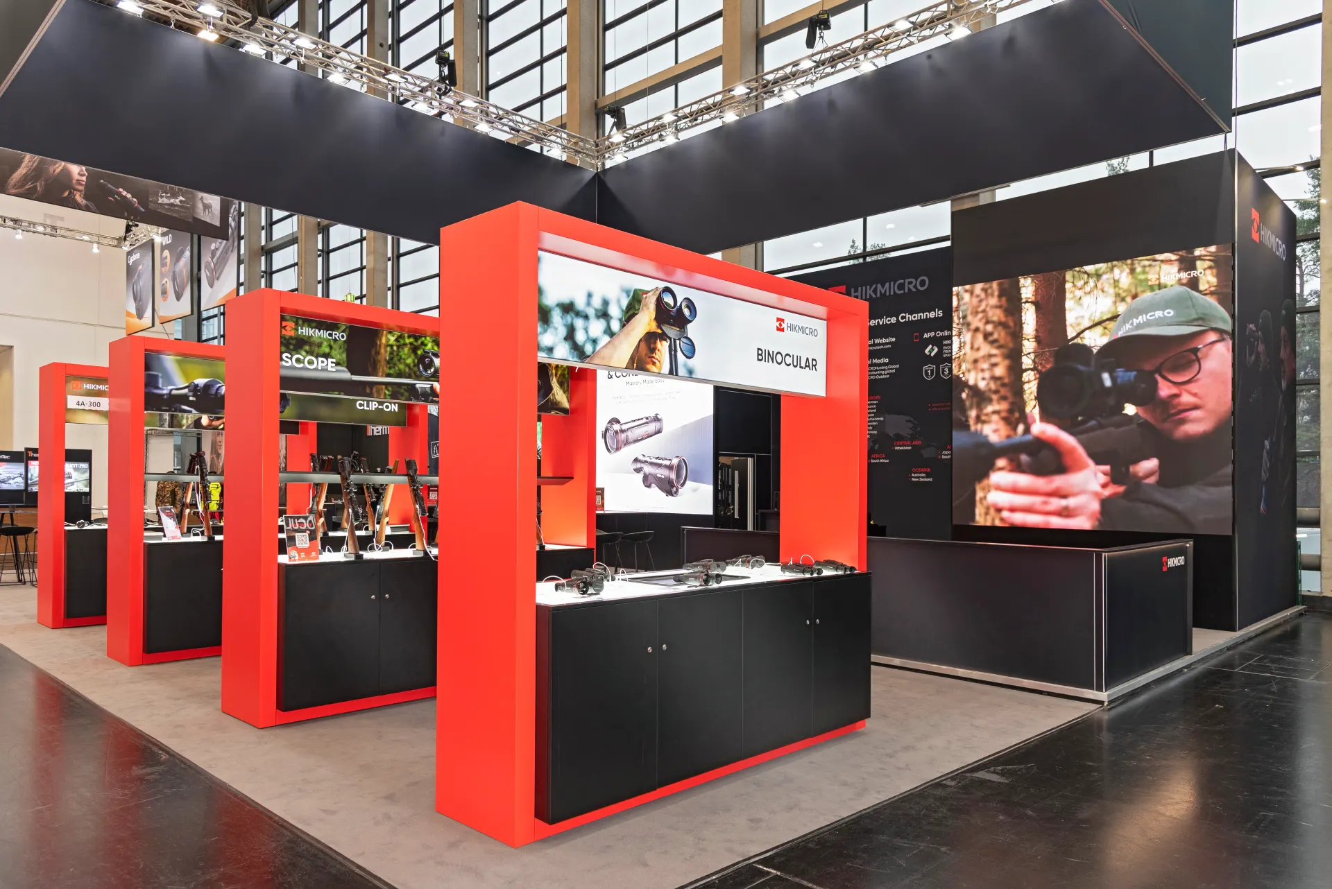 Präsentationsmodule von HIKMICRO mit Ferngläsern und Zielfernrohren, rotes Design auf der IWA 2025 – Messebau Nürnberg.