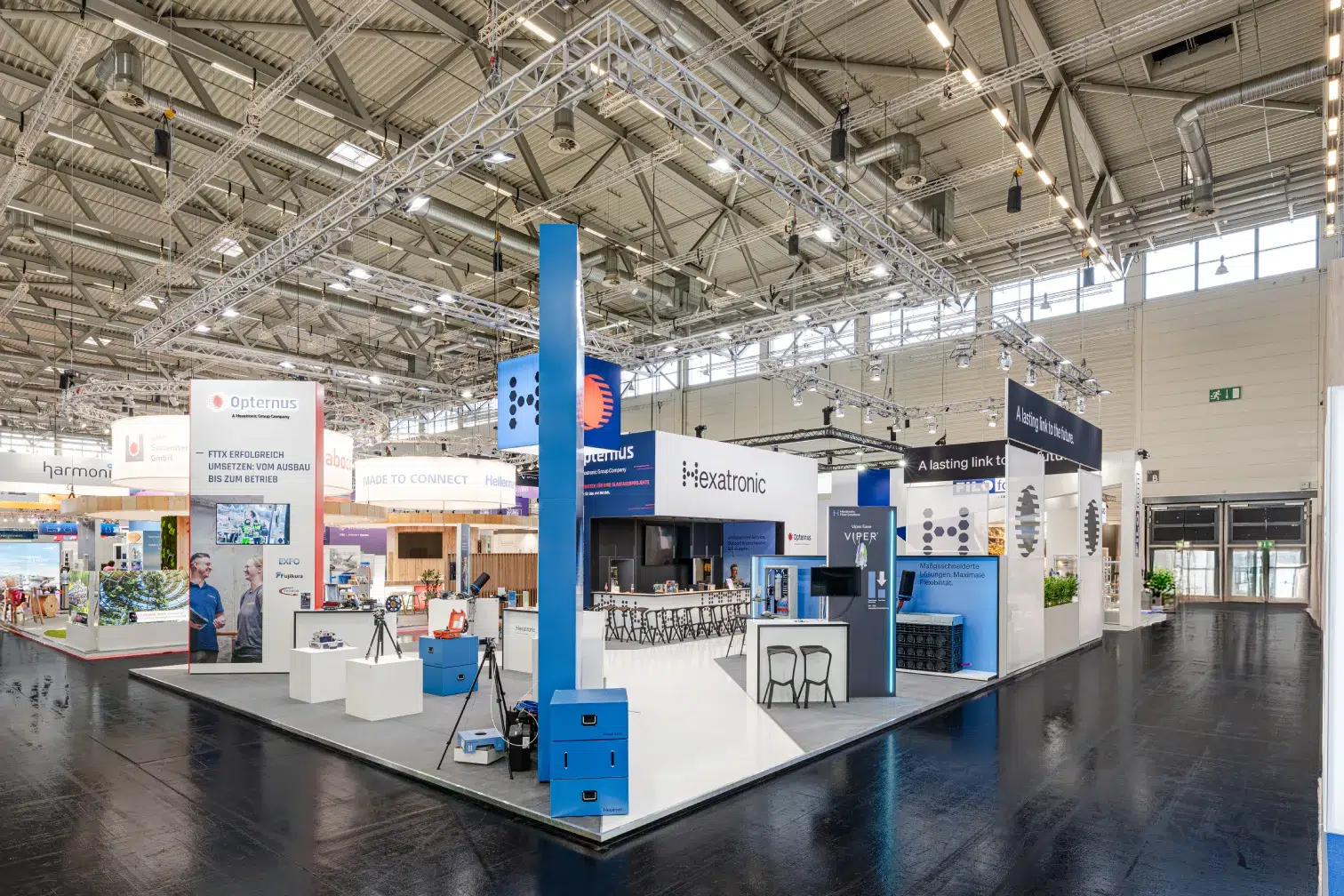 Messebau Köln – Gesamtansicht des Hexatronic Messestands mit offener Architektur auf der AngaCom 2025.