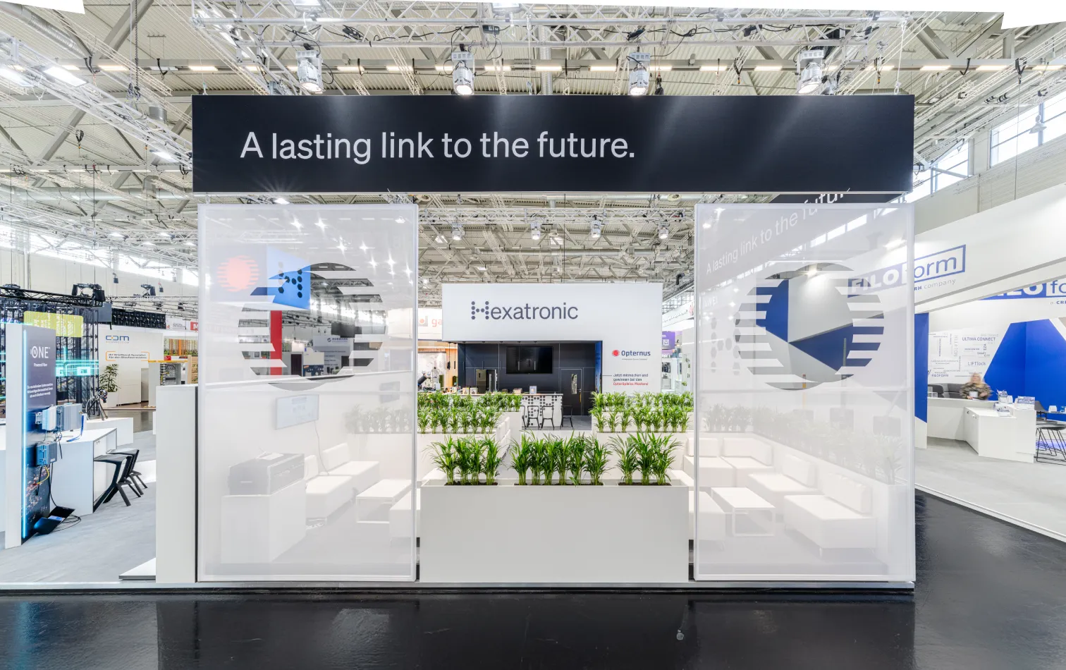 Messebau Köln – Eingangsbereich des Hexatronic Messestands mit Glas- und Pflanzen-Elementen auf der AngaCom 2025